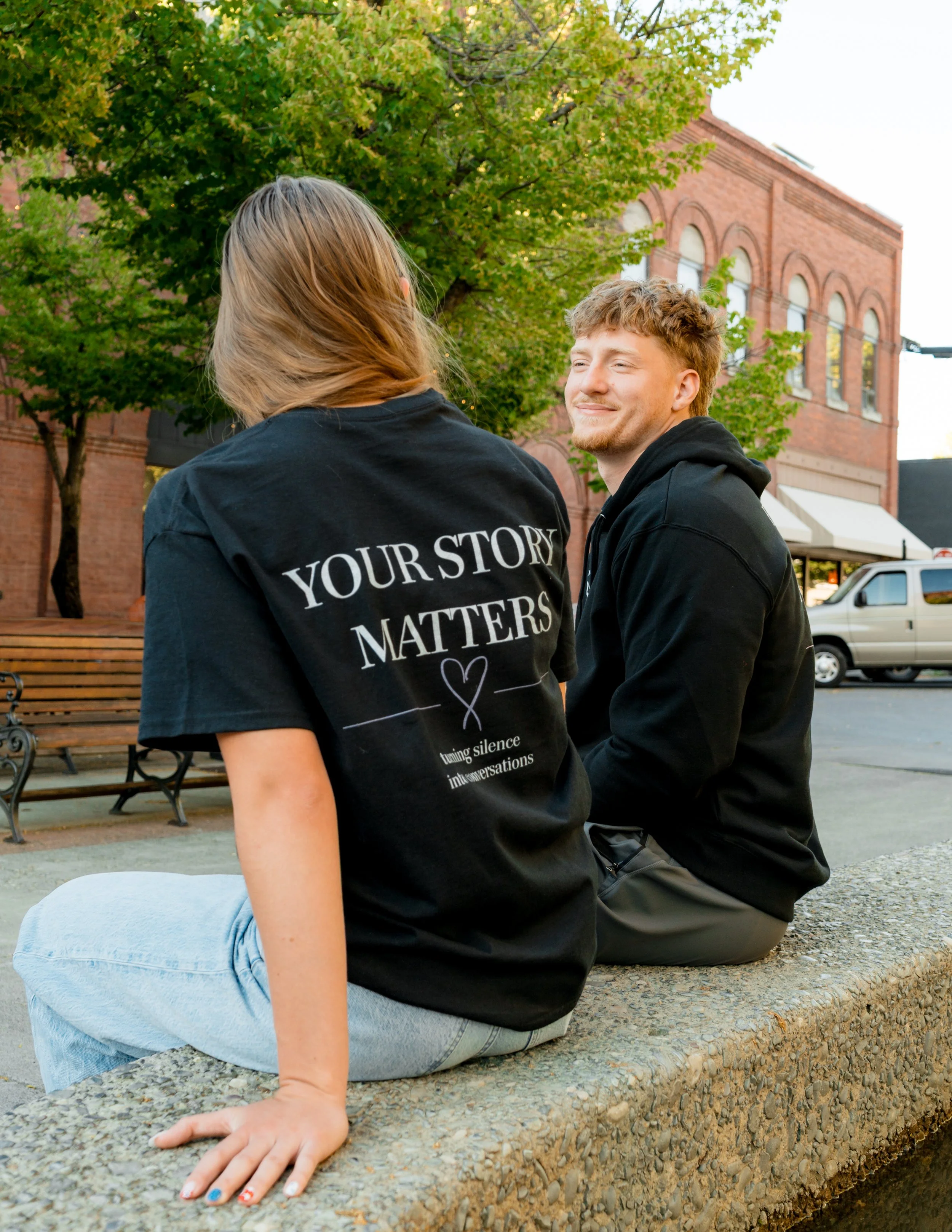 Two people wearing StandUp33 awareness apparel while sitting together outdoors.
