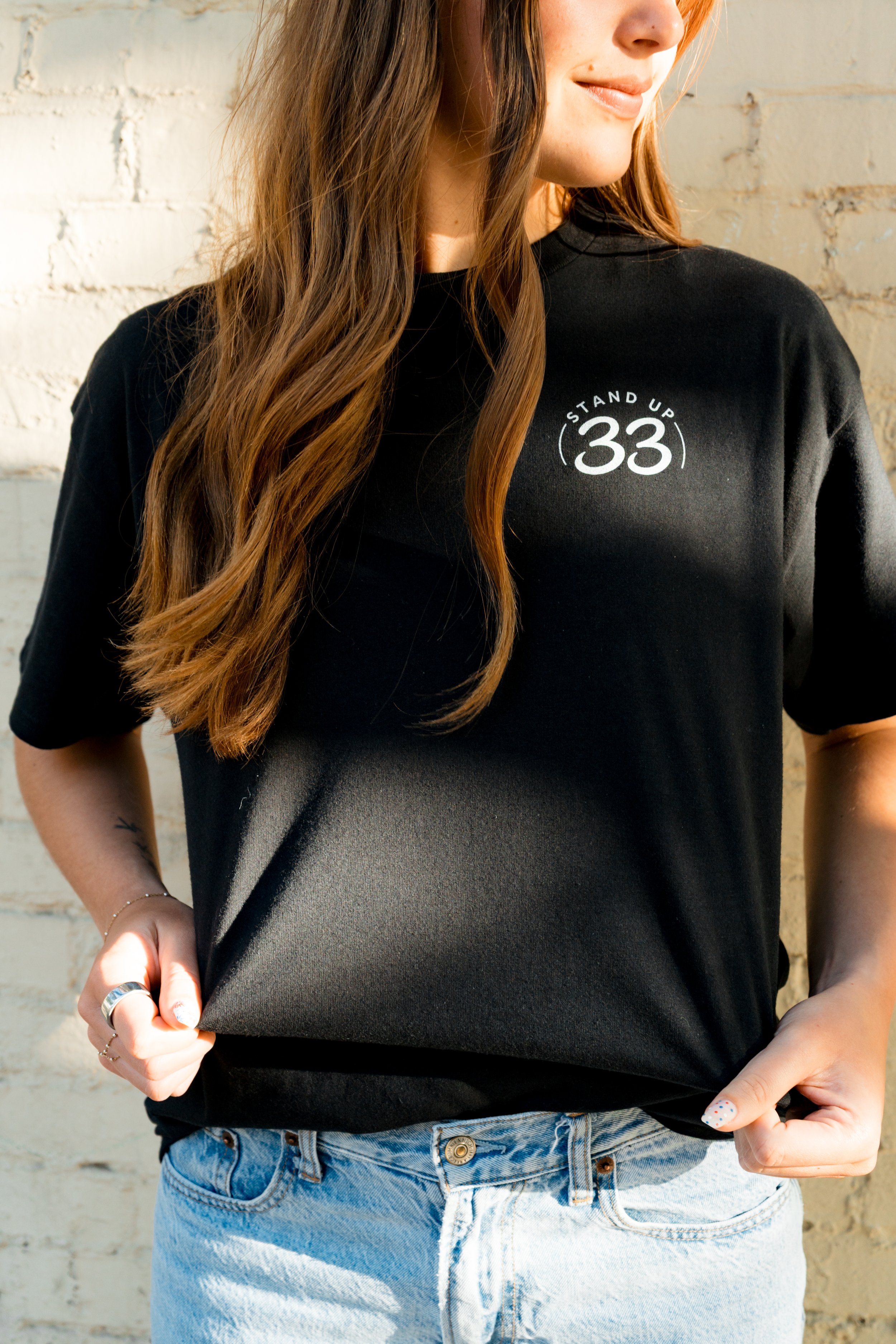 Front of a person wearing a StandUp33 T-shirt with the StandUp33 logo.