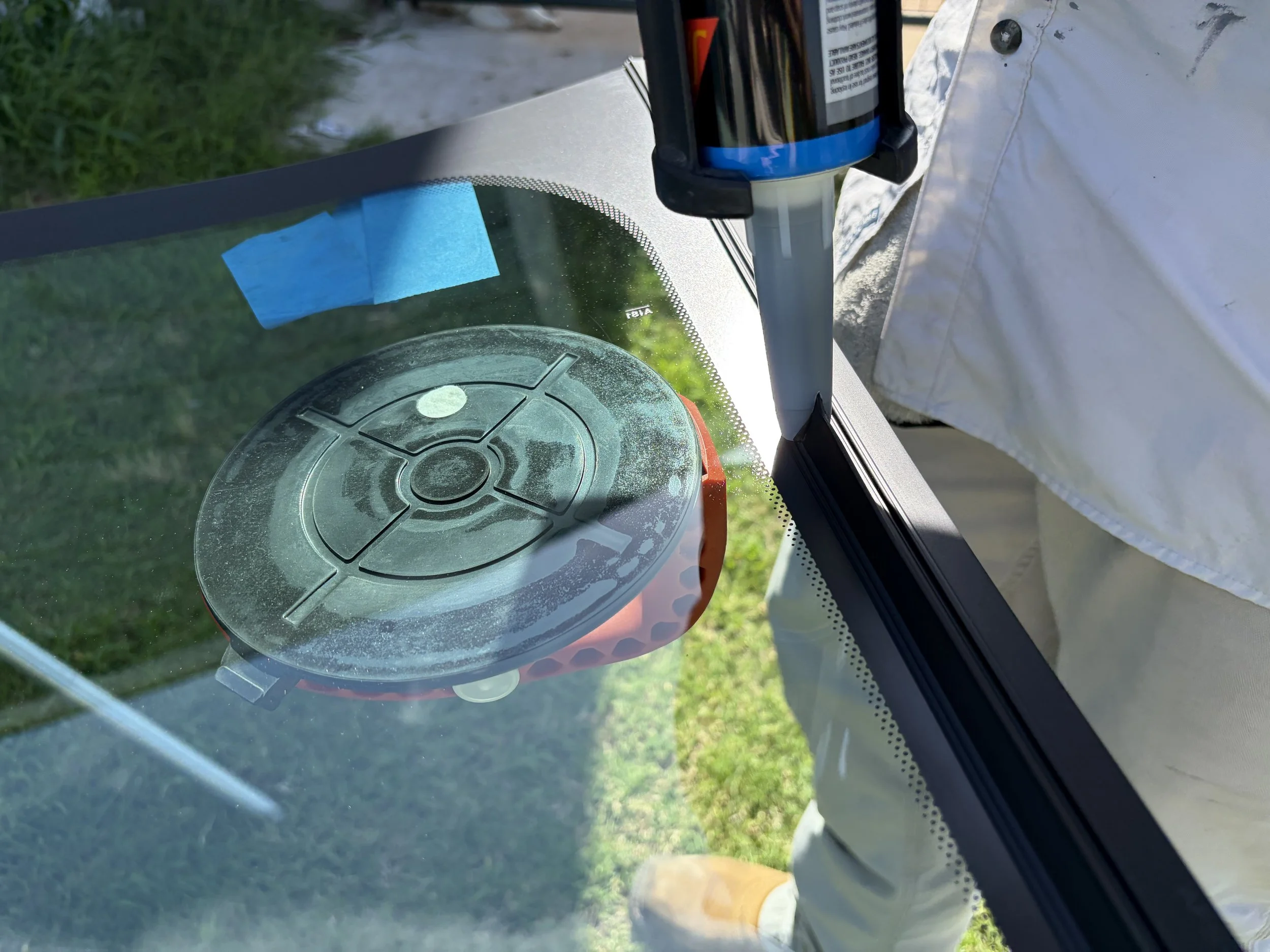 A windshield with urethane being applied just before it is to be installed. The urethane is being applied to the glass and a suction cup is visible.