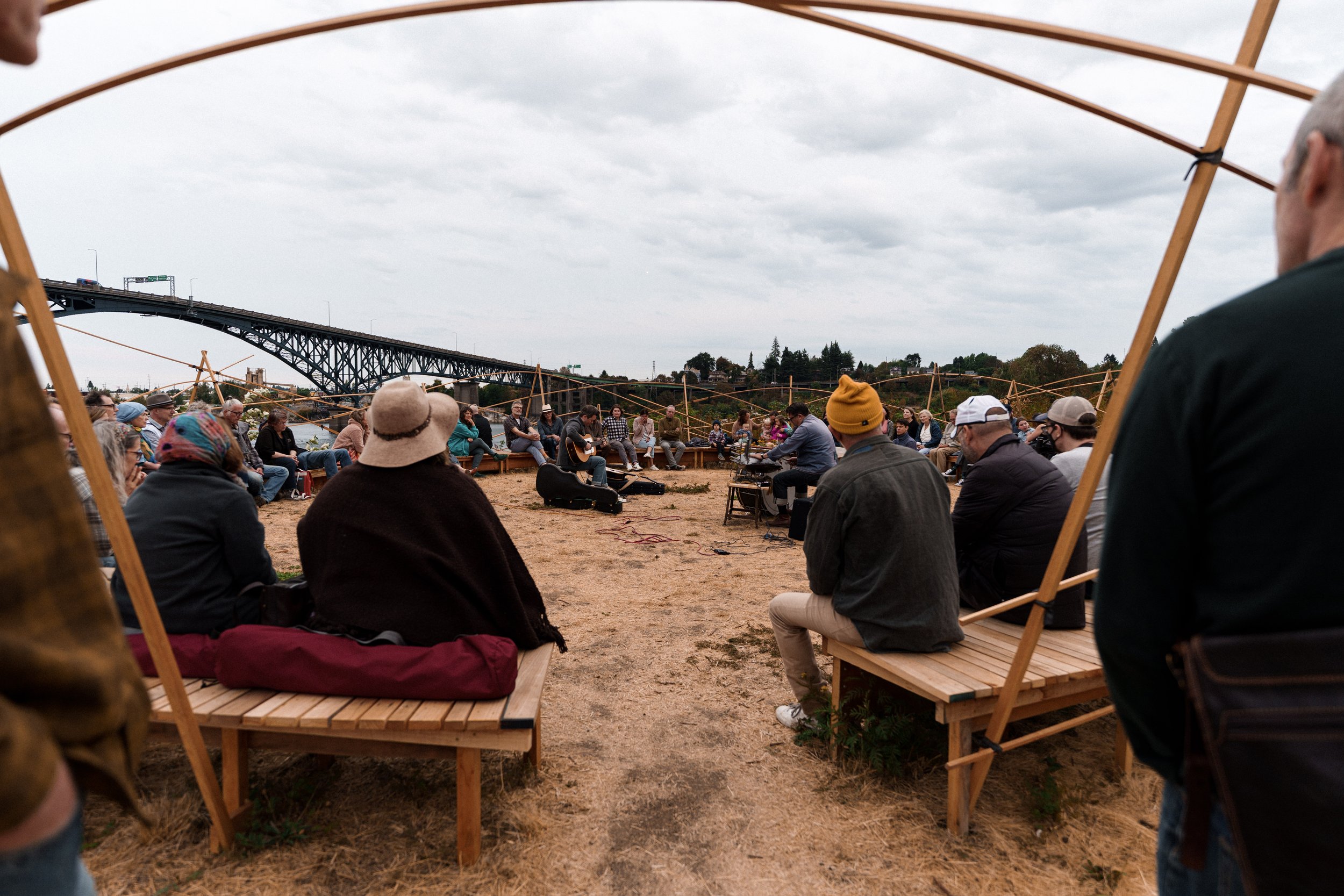 The entrance to a circular bench structure on the banks of the Willamette River with the Ross Island Bridge in the background - a piece by sculptor Philip Krohn with a sound installation by Seth Nehil.
