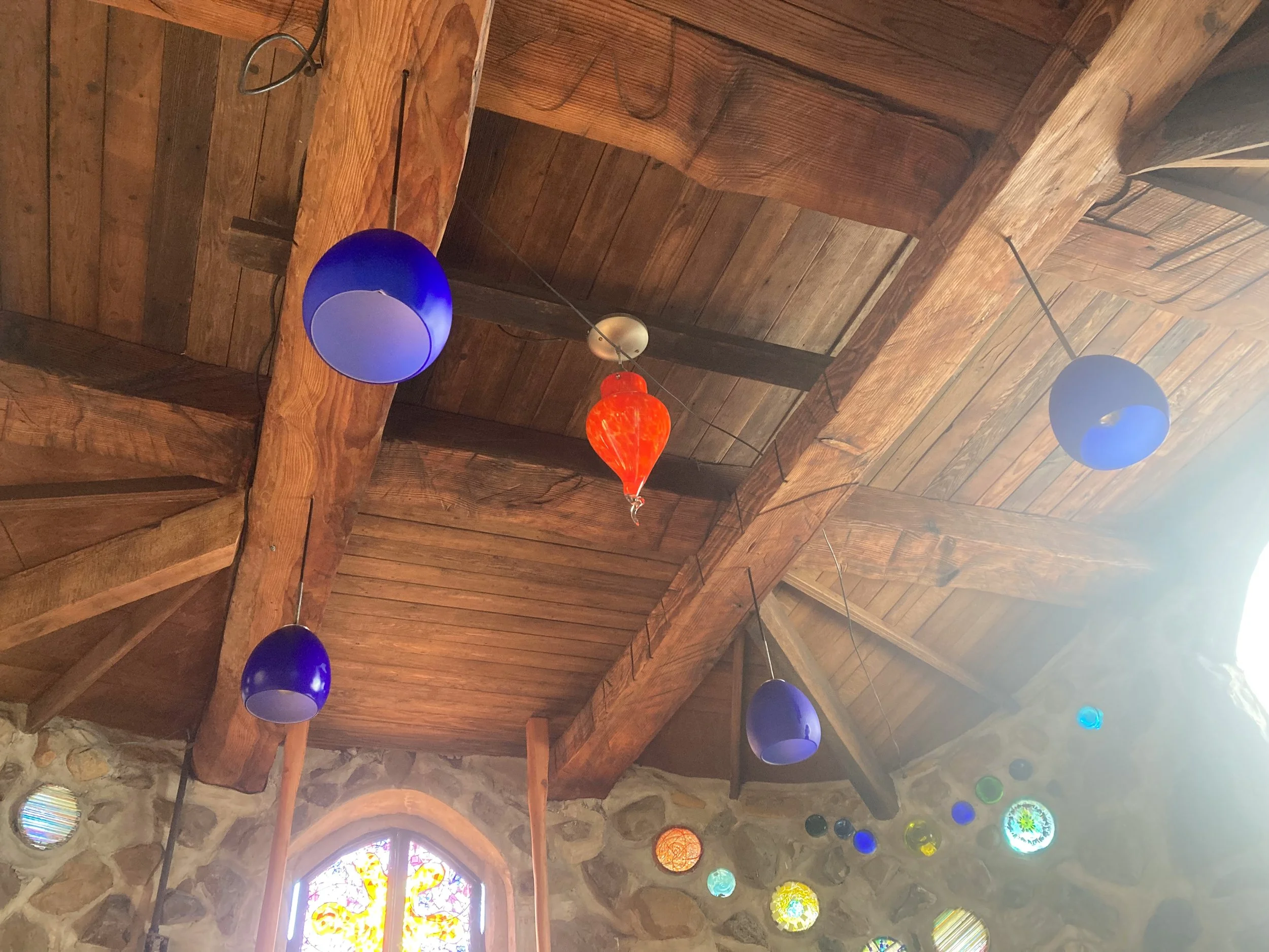 Heavy hand-hewn support beams and colored glass light fixtures.