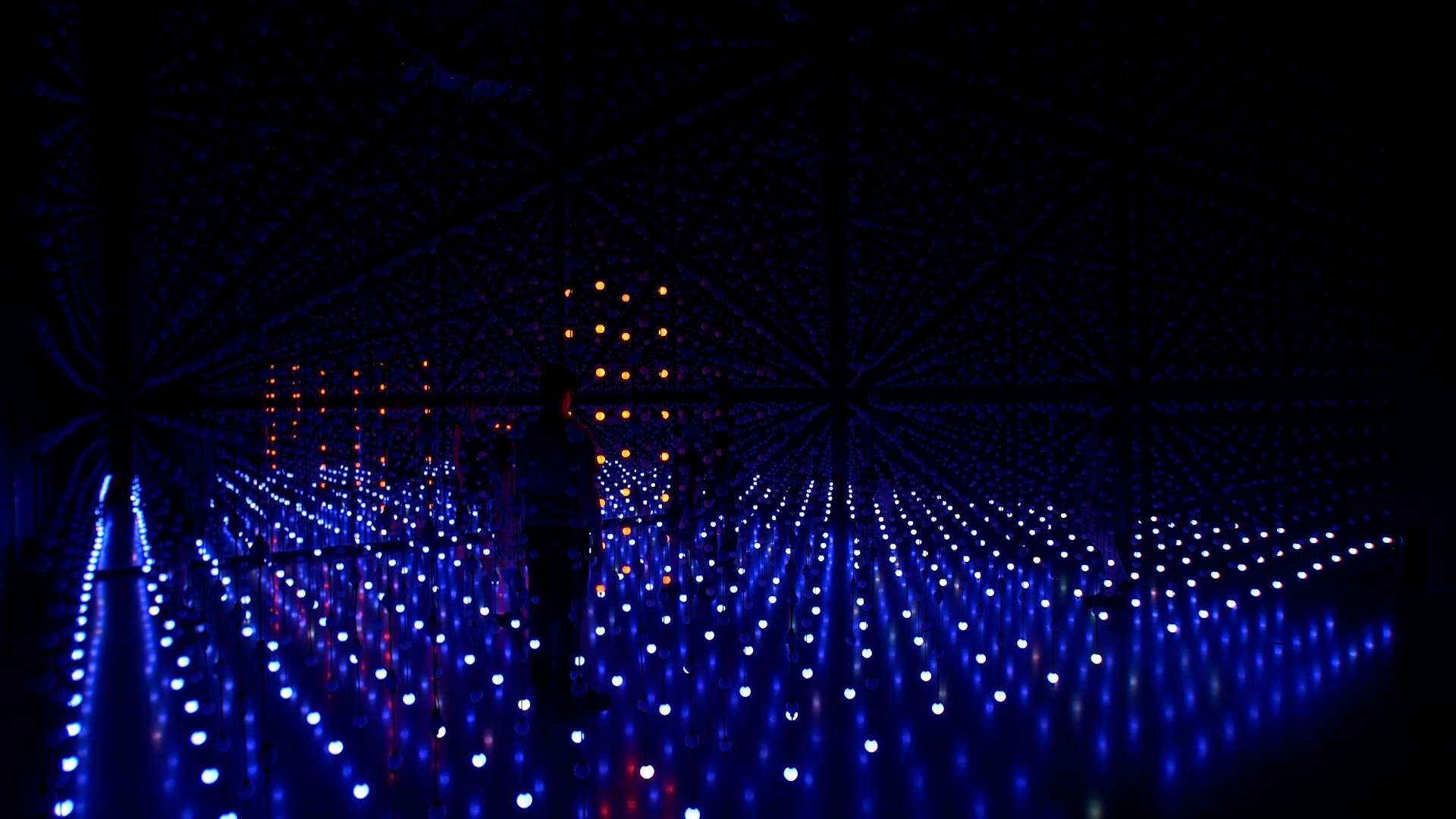 Silhouetted figures stand within a red and blue LED grid installation — Unknown Atmospheres by Seth Nehil and Parallel Studio at Hopscotch Gallery