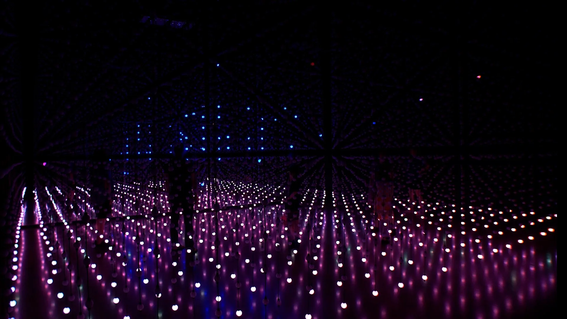 Silhouetted figures stand within a red and blue LED grid installation — Unknown Atmospheres by Seth Nehil and Parallel Studio at Hopscotch Gallery