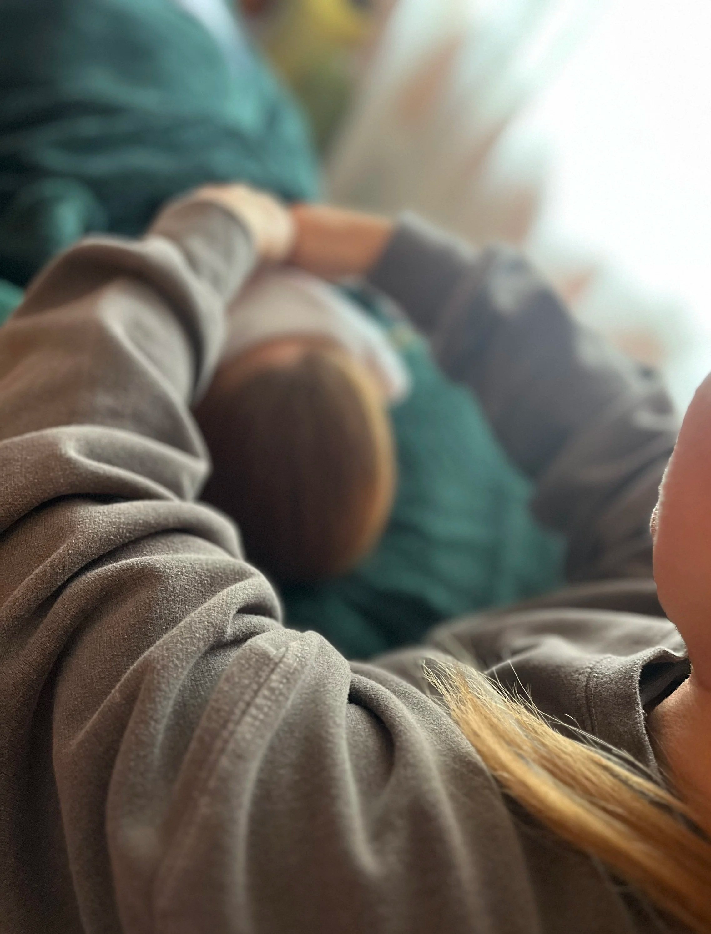 Close-up view of a person's arms holding their hands above a client's face on a Reiki therapy bed.