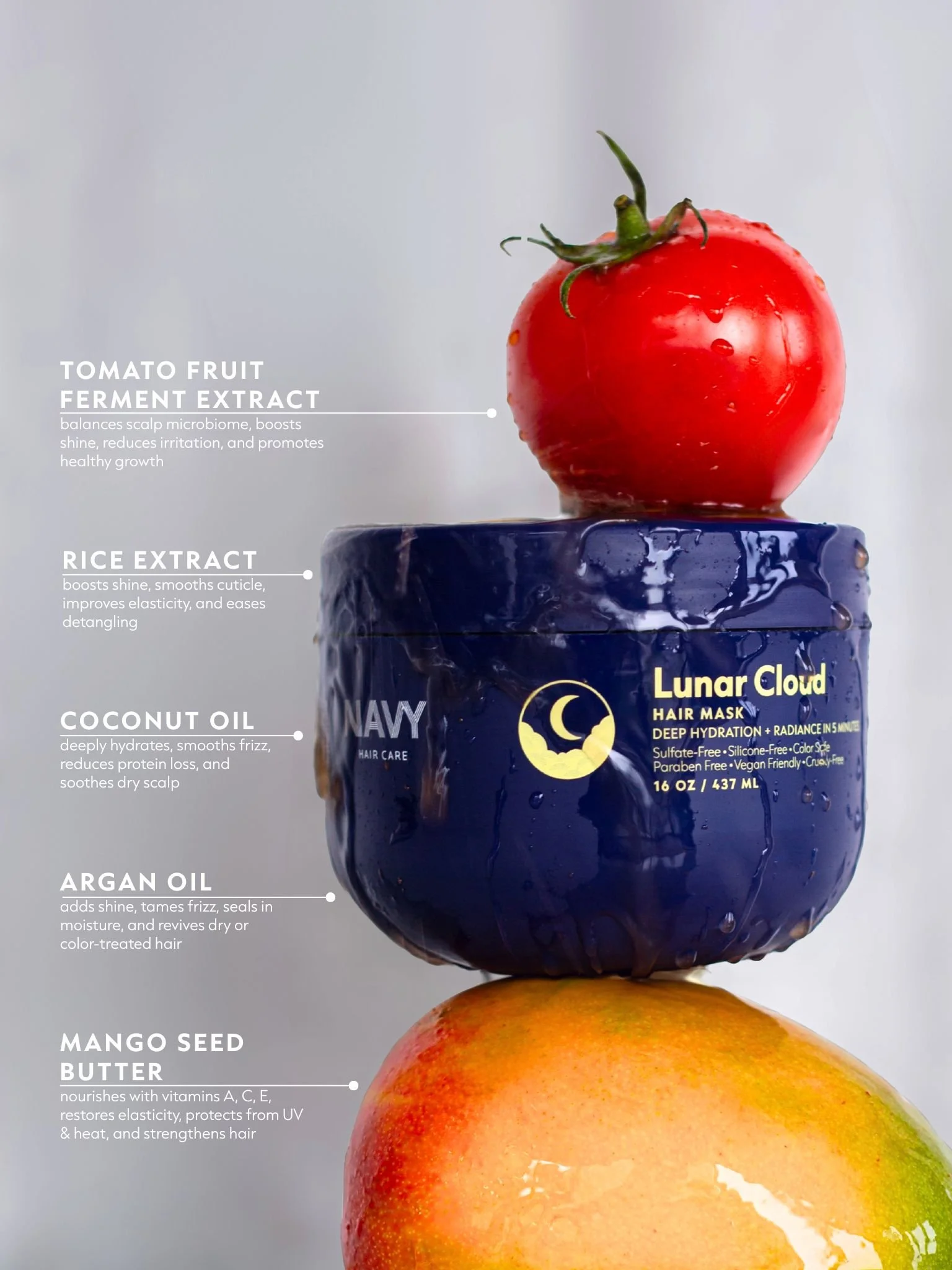 Close-up of a red tomato with green stem on a dark blue container, with text overlay describing natural ingredients like tomato ferment extract, rice extract, coconut oil, and mango seed butter, highlighting benefits for hair care.