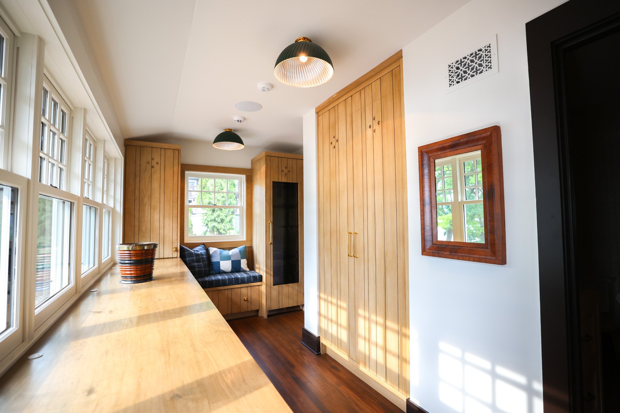 Interior of a room with wooden paneling, large windows, and a hanging light fixture.