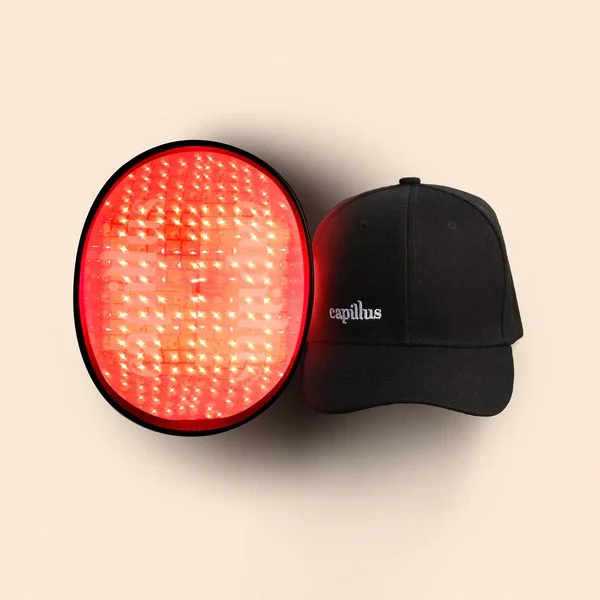 A black cap with white text next to a red LED traffic signal device on a beige background.