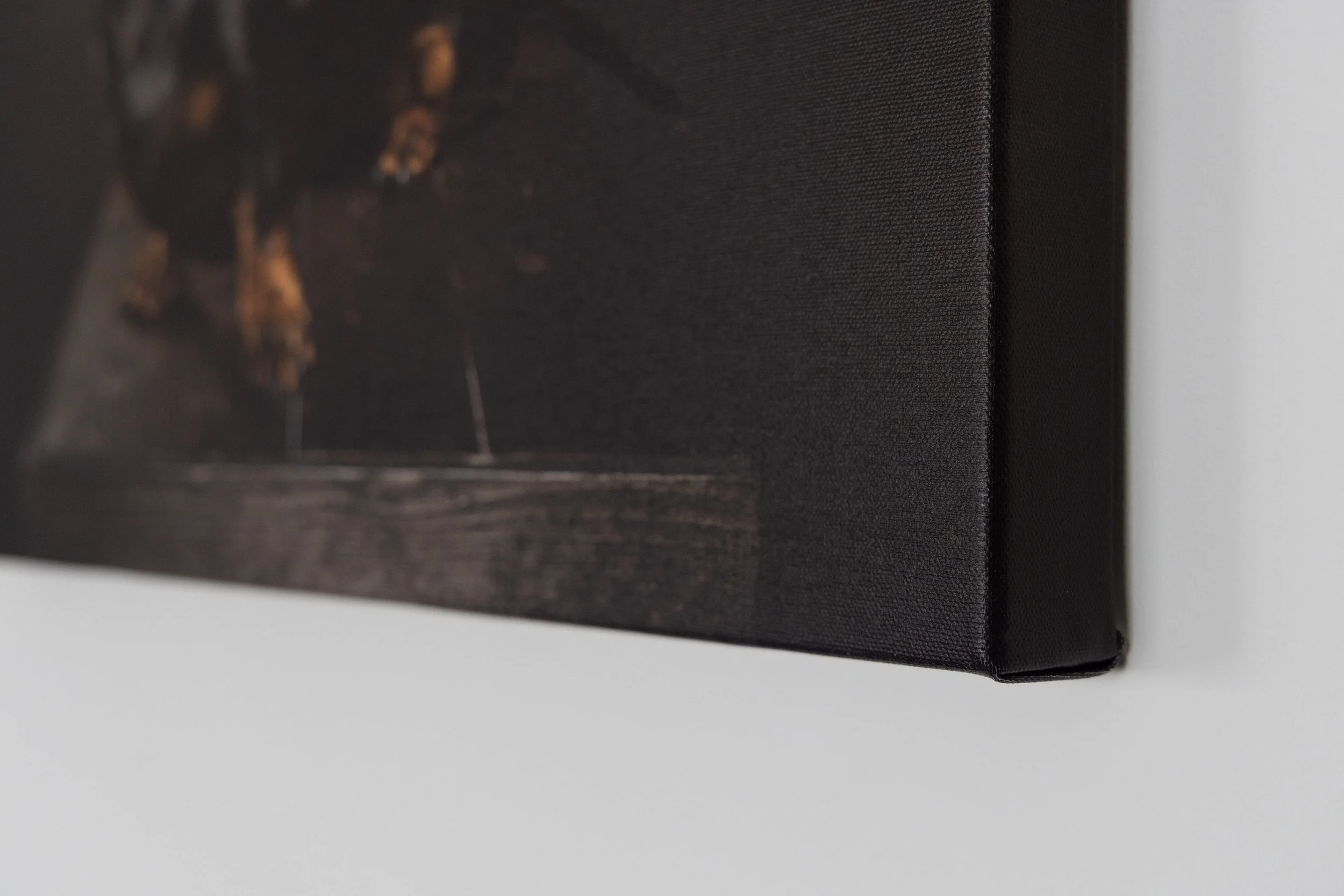 Close-up photograph of a black book or box with textured surface, leaning against a wall or white background.