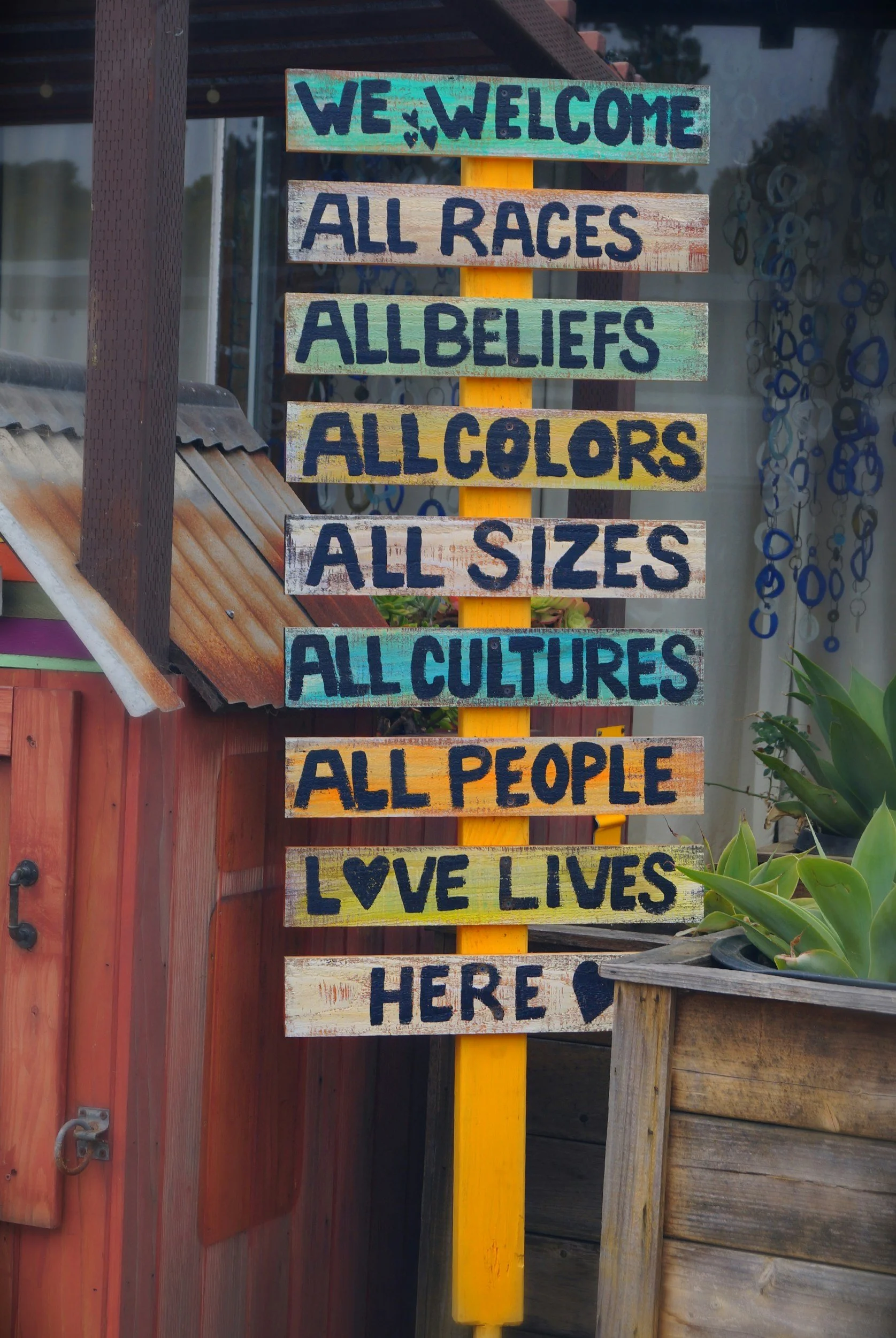 sign stating "We welcome, all races, all beliefs, all colors, all sizes, all cultures, all people. Love lives here.