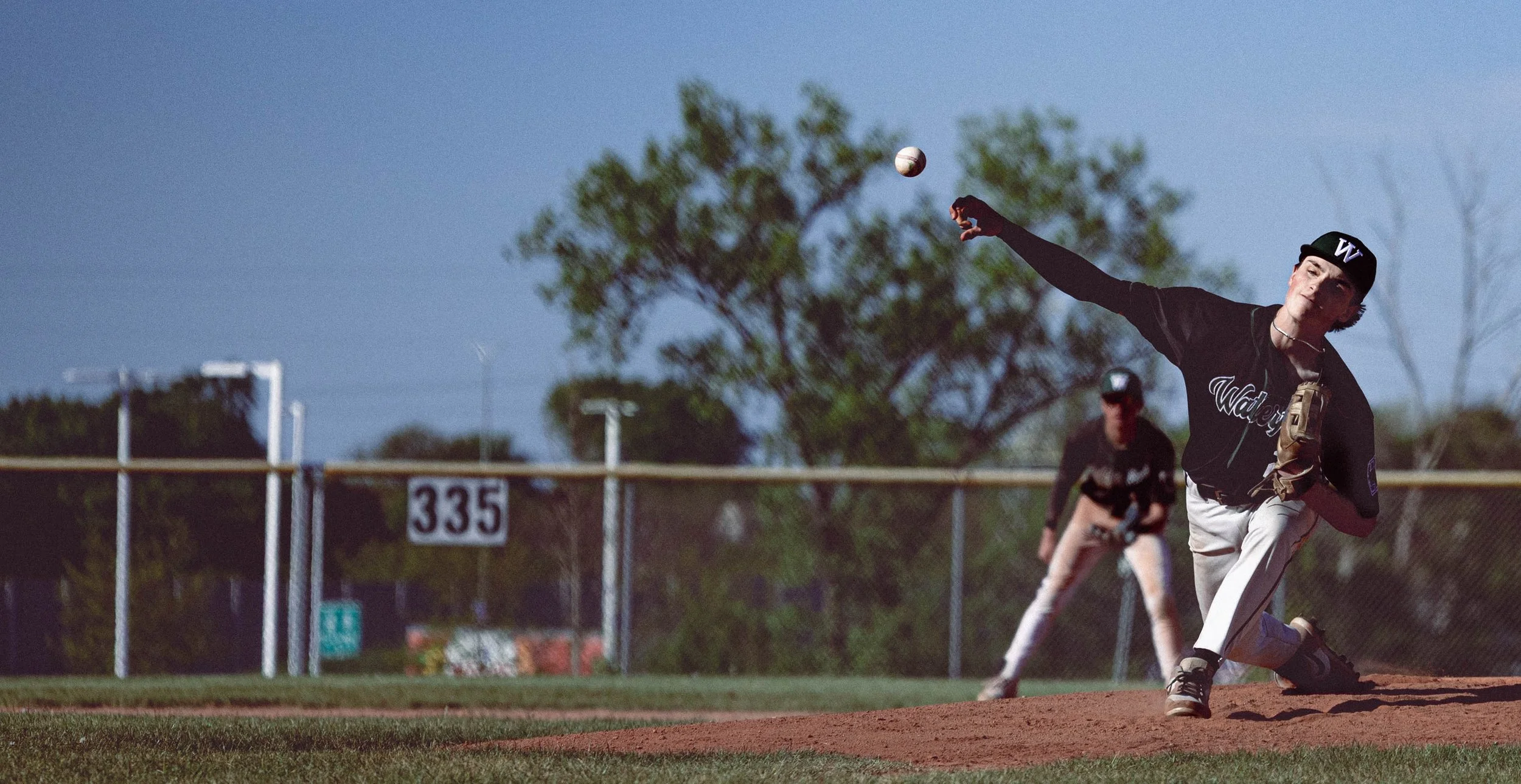 A young male baseball player is pitching a ball during a game called a baseball game.