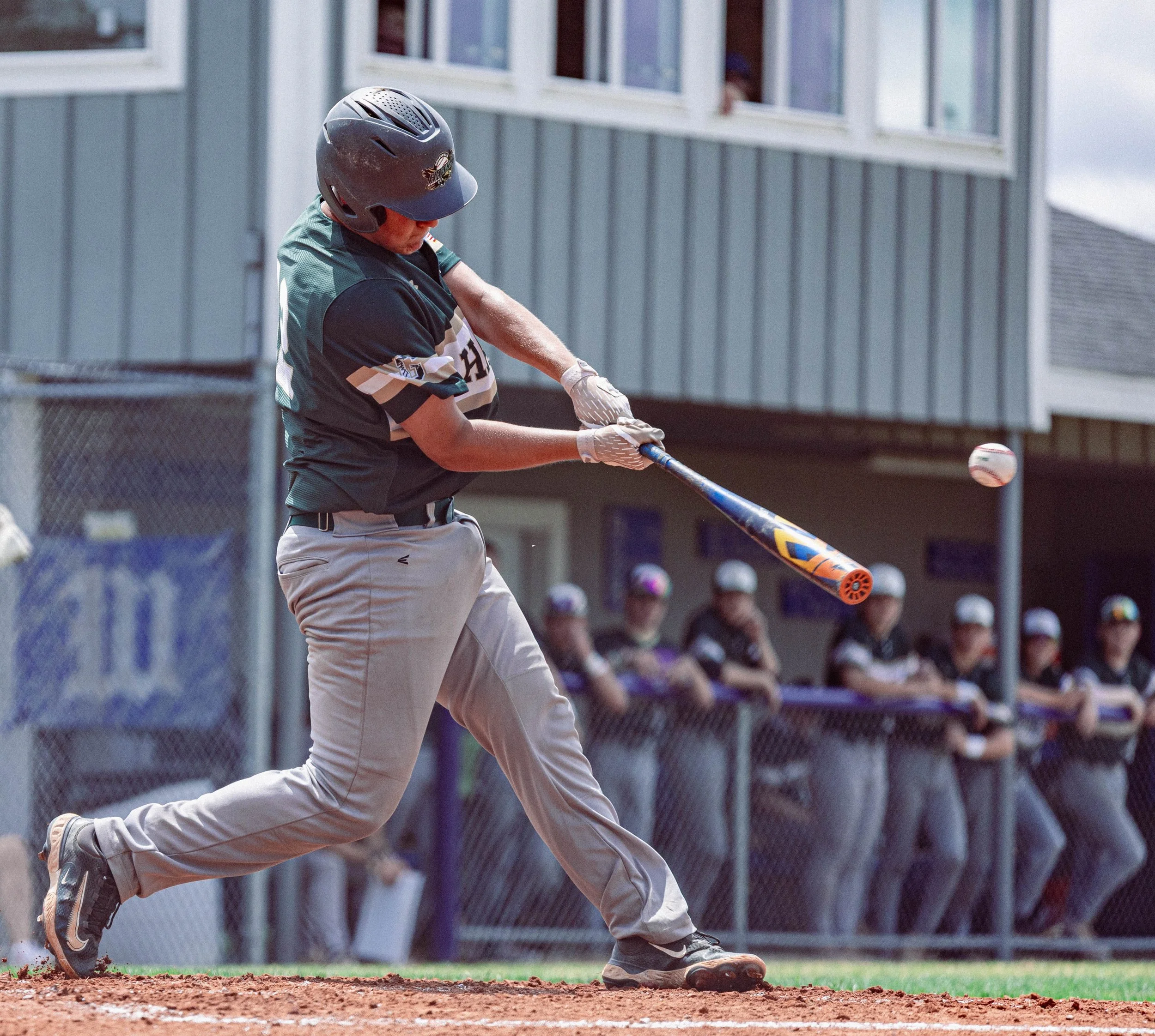 A baseball player is running on the field, wearing a helmet and a uniform, hitting the baseball with a bat during a game.