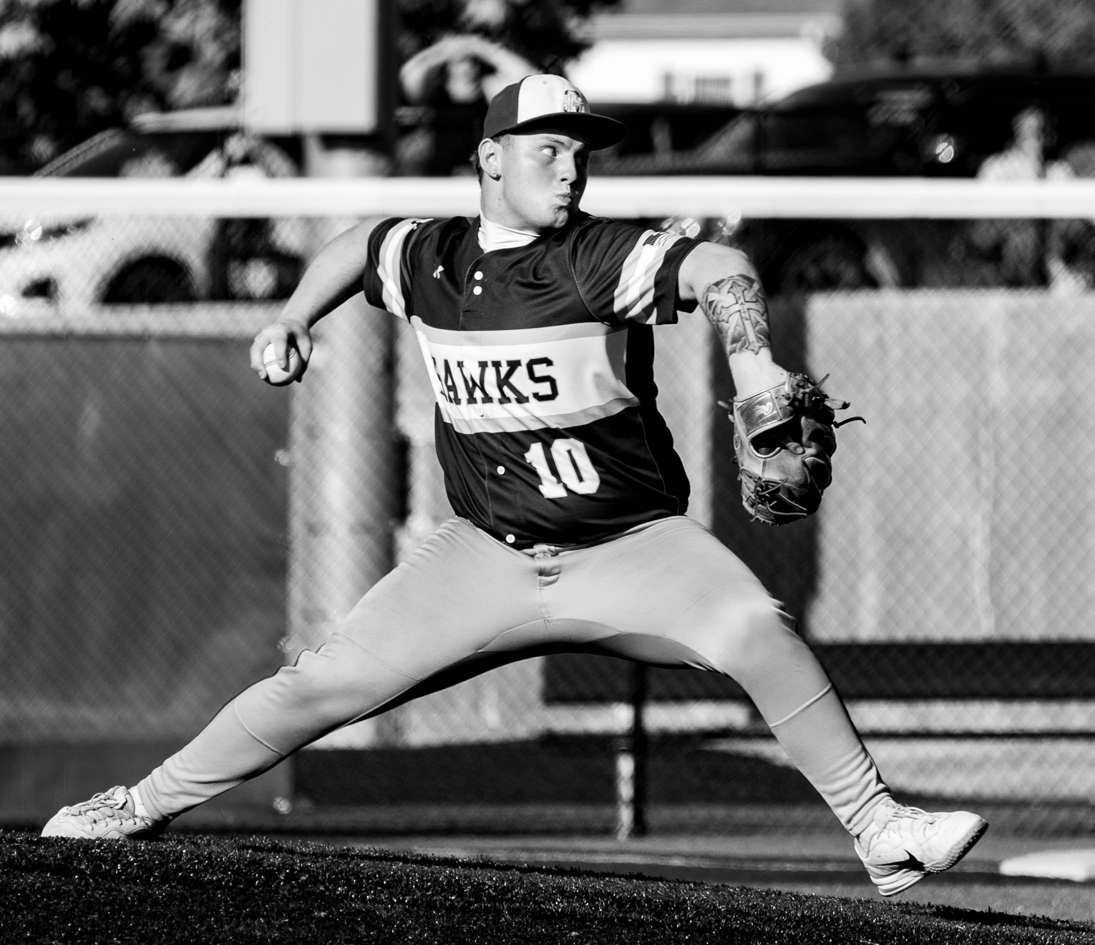 A female softball player in a Hawks uniform preparing to catch a ball wearing a cap, glove, and athletic attire on a baseball field.