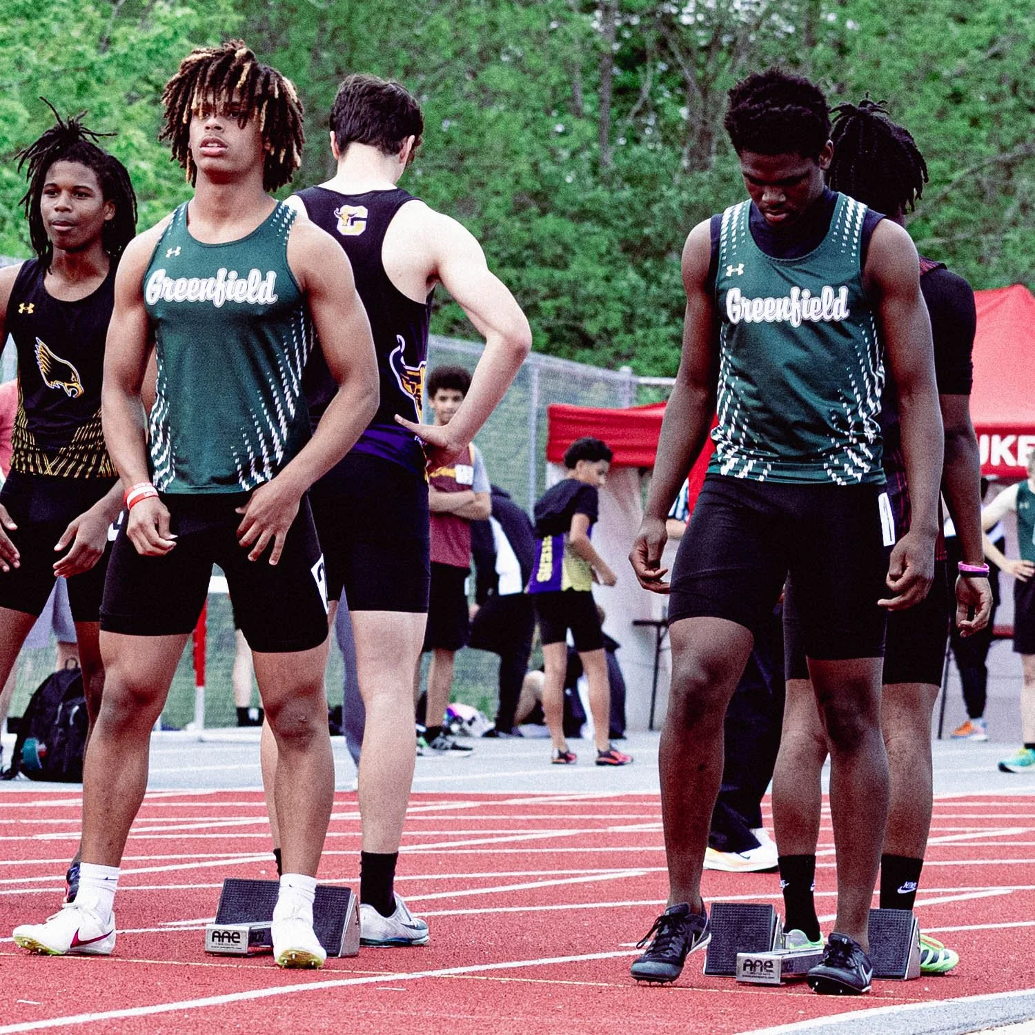 Track athletes preparing at the starting blocks during a race event at a sports track field.