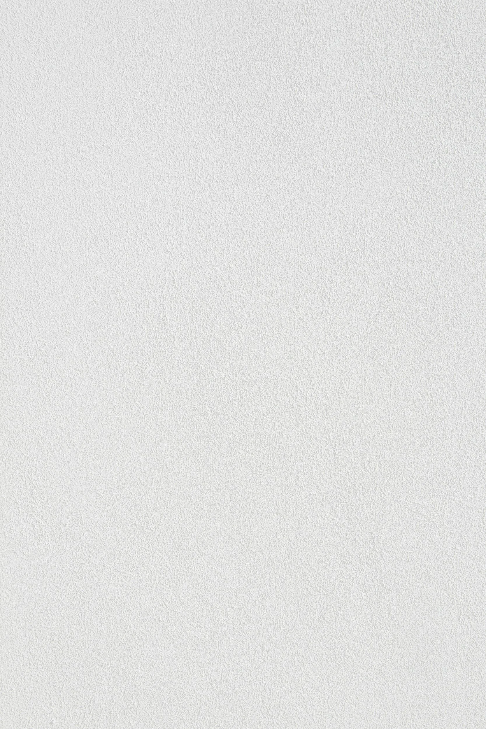 Empty white textured wall with a ceiling light.