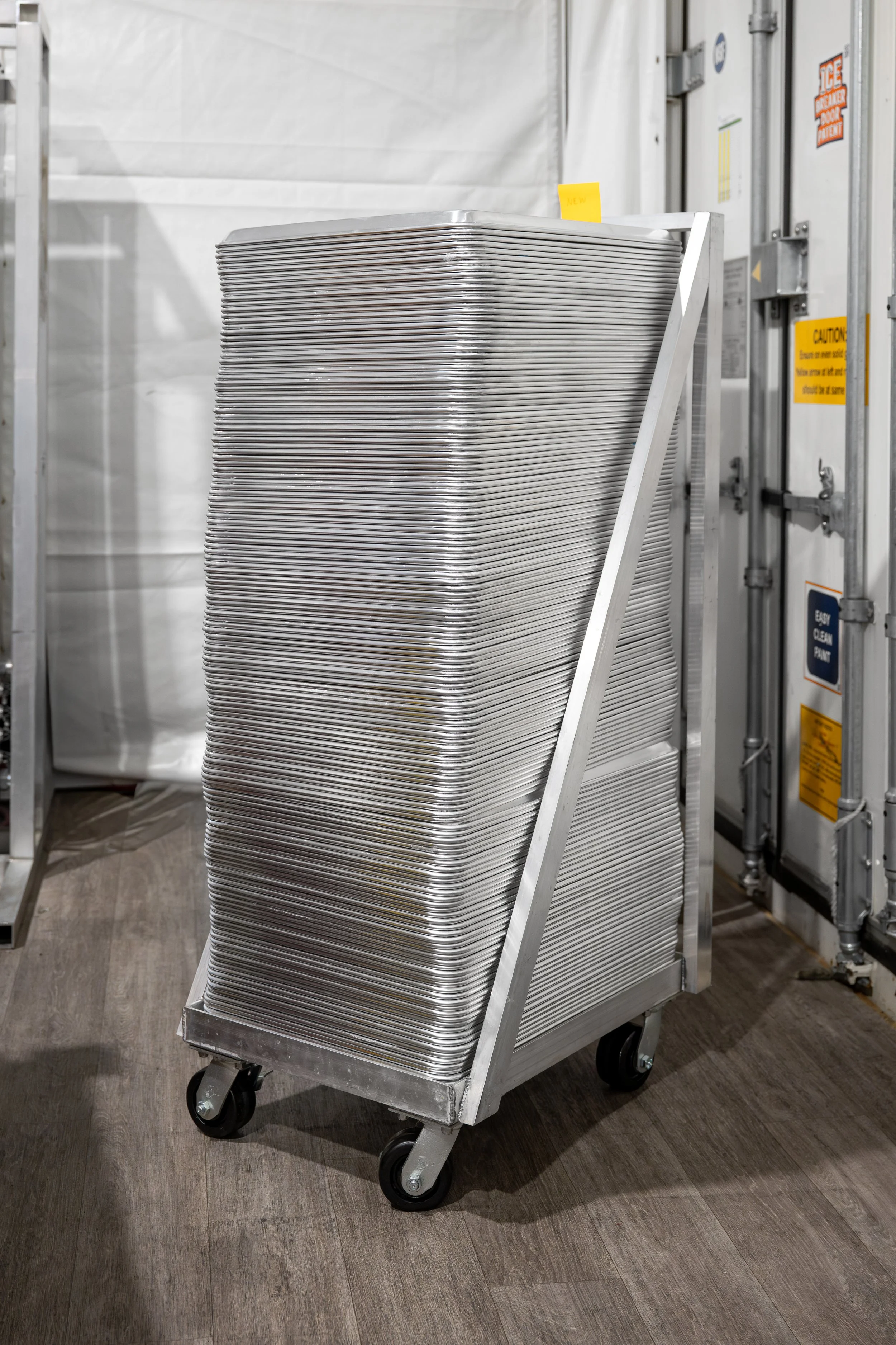 A custom cart filled with stacked metal trays in a storage or kitchen area.