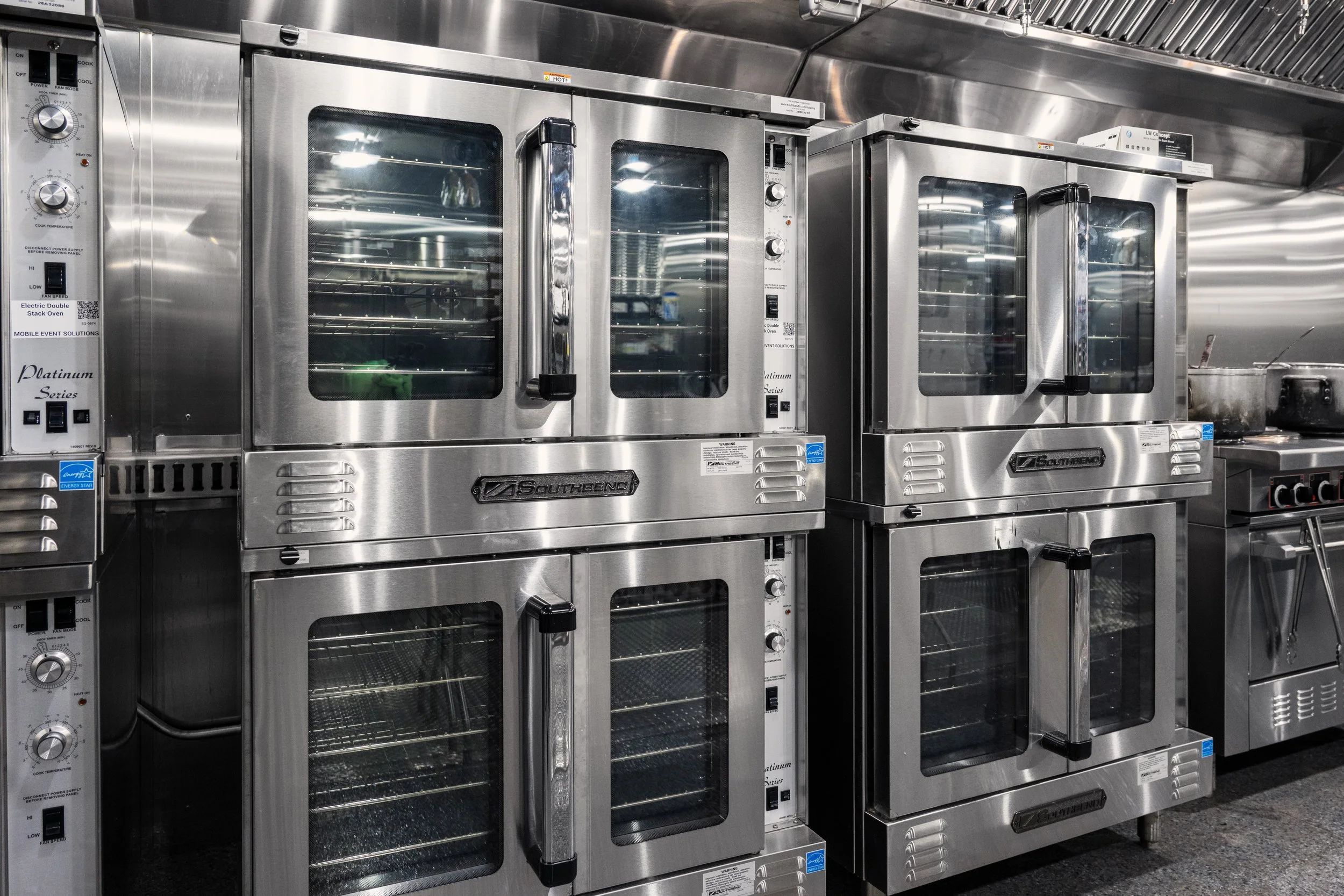 Stainless steel commercial ovens in a temporary kitchen.