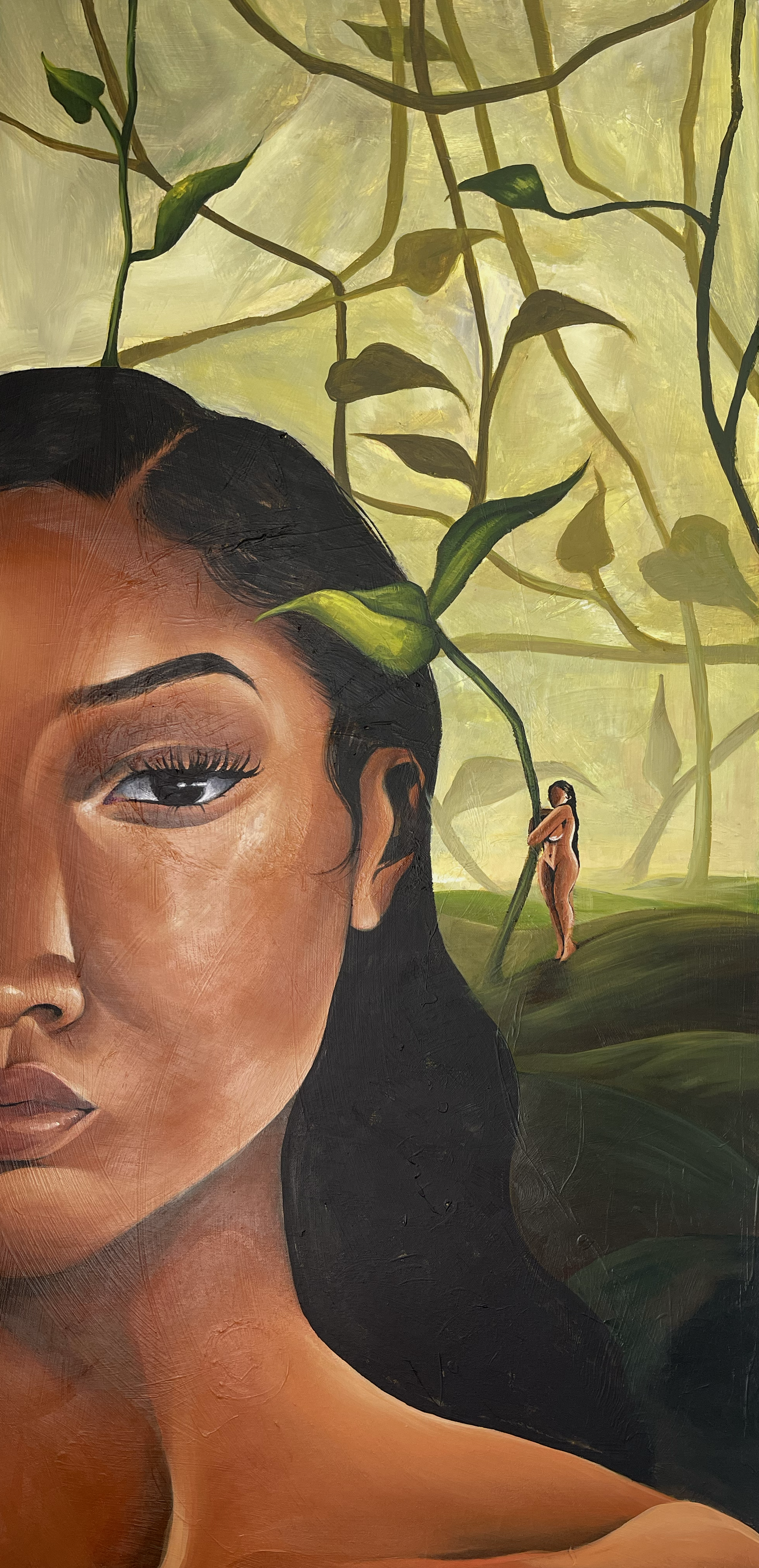 Close-up of a woman with dark hair and brown skin in front of a green, leafy background. There is a small, nude figure holding a large leaf in the background.