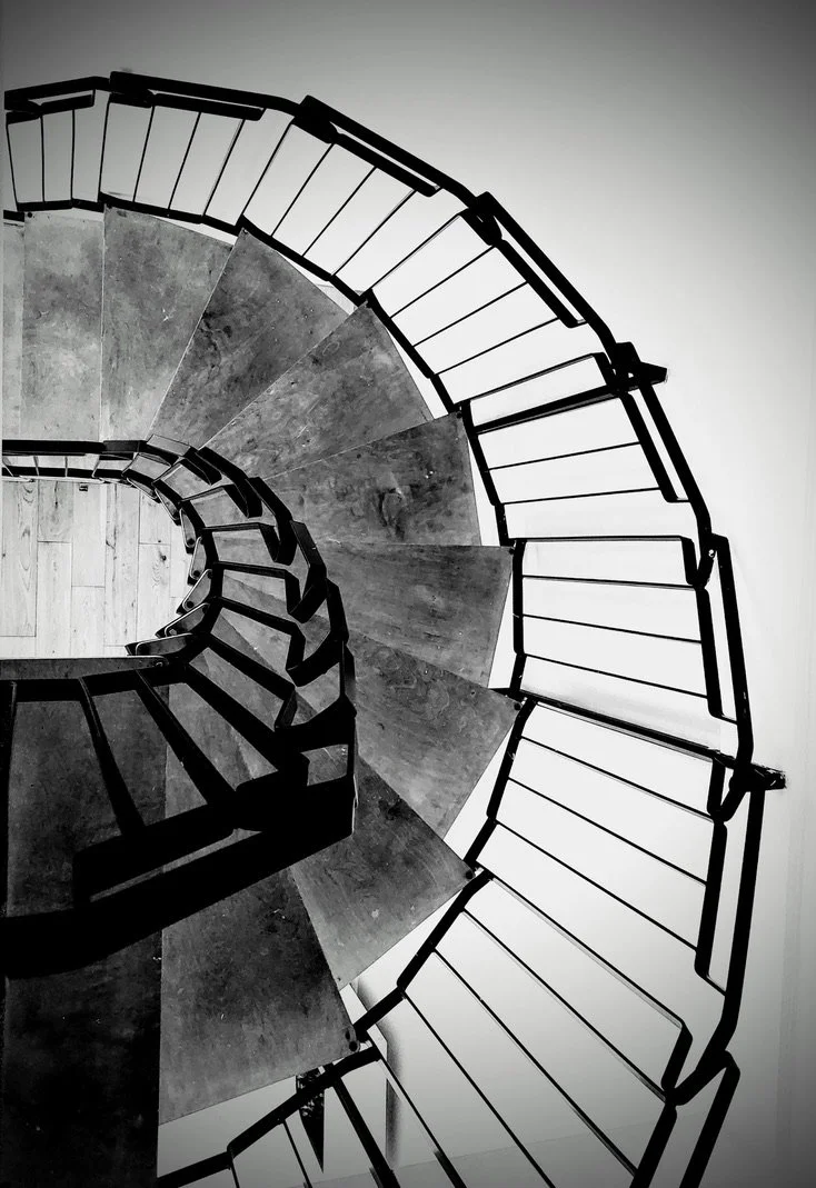 This spiral staircase, captured in black and white, draws the eye inward through its graceful curves and contrasting shadows.