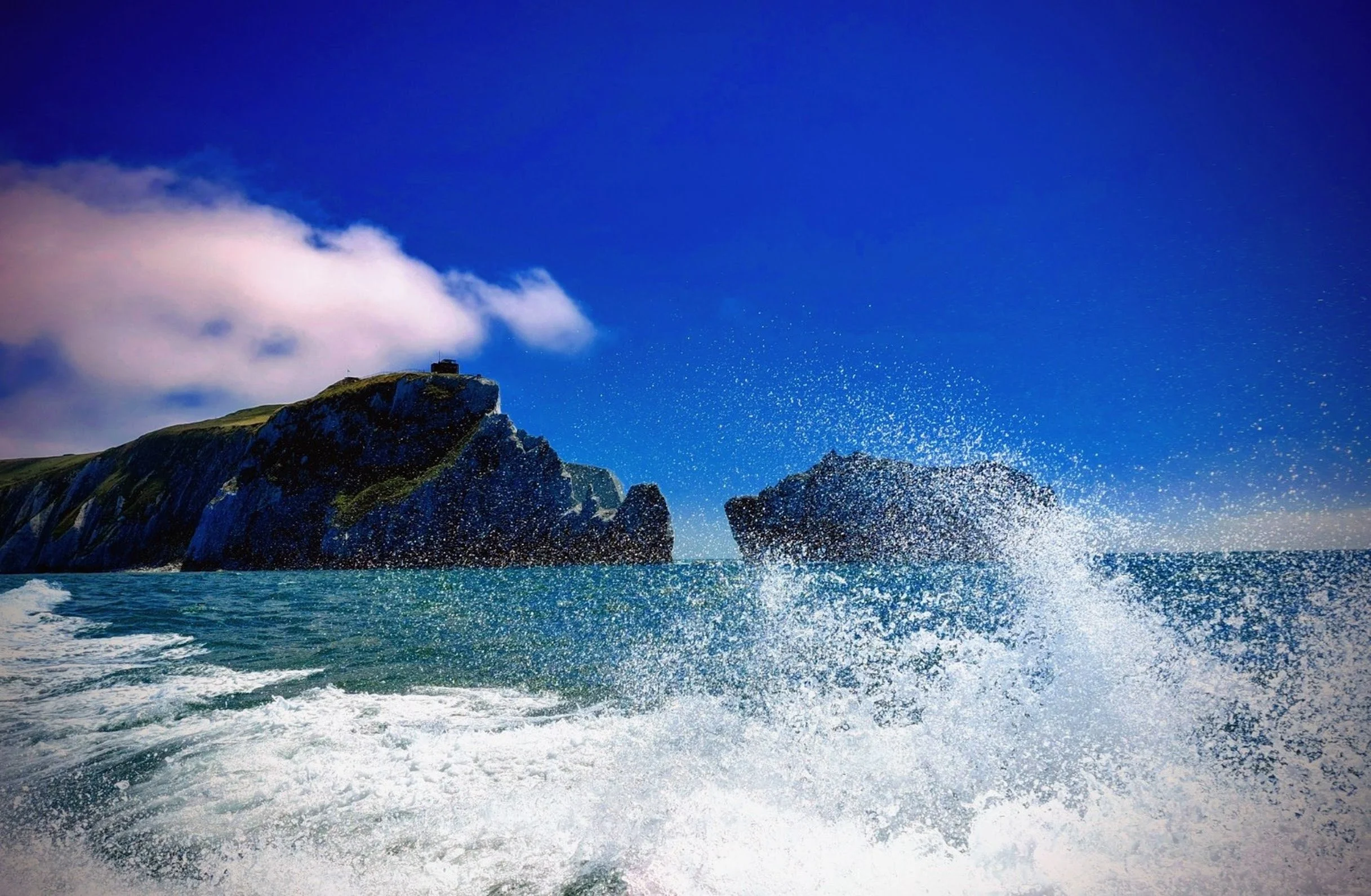 Crashing waves, rocky cliffs, turquoise water and cobalt sky joining together to create one image.