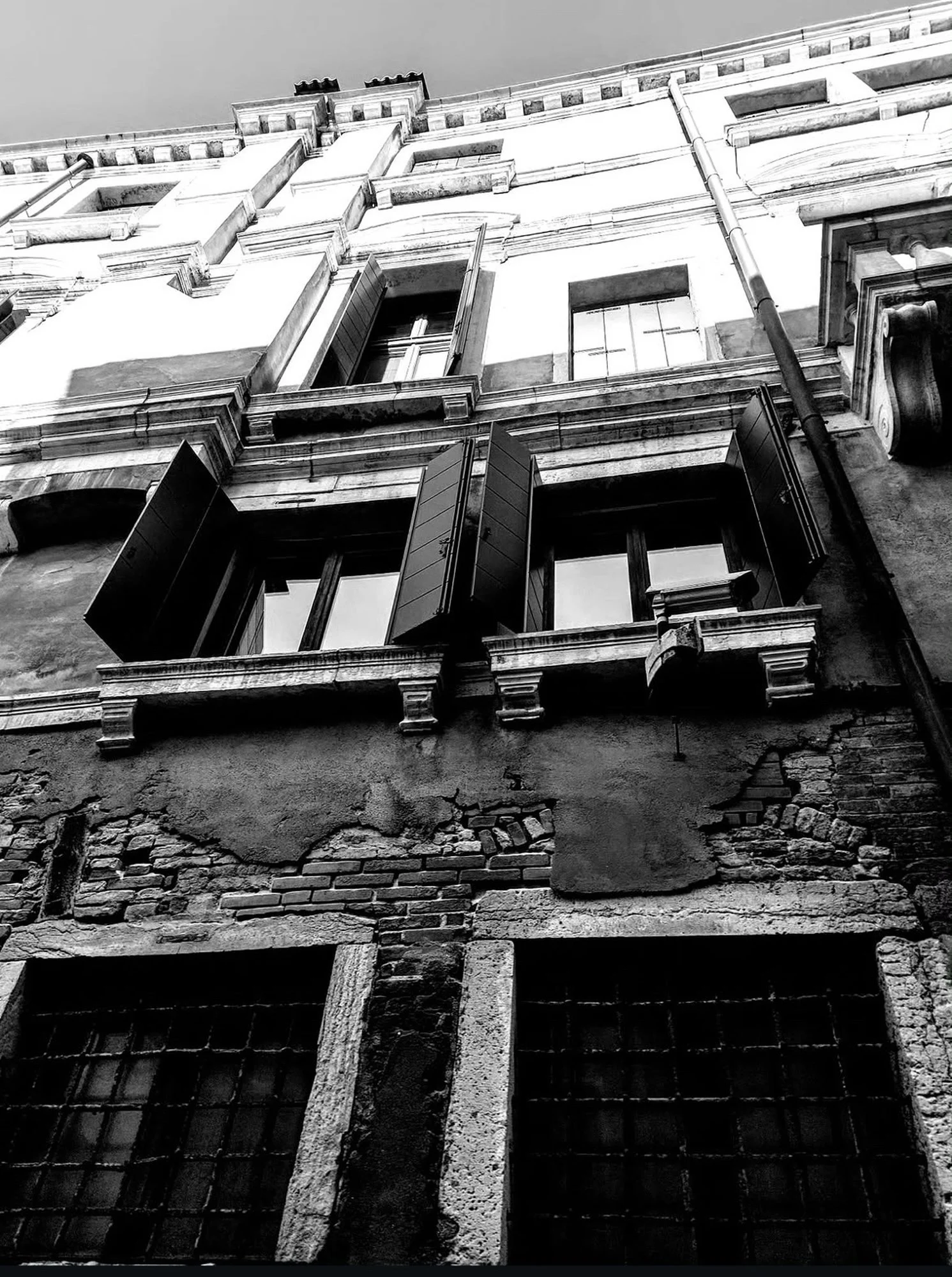 Black & white photograph of a Venetian building facade, showing windows & architectural details