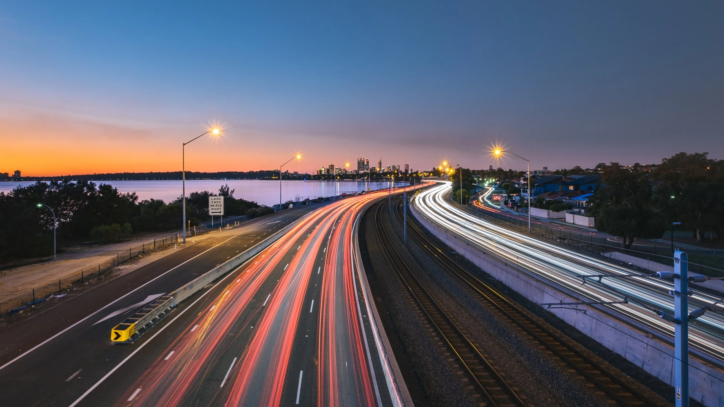 A highway leading into a city in the background, with blurred headlightss and tail lights