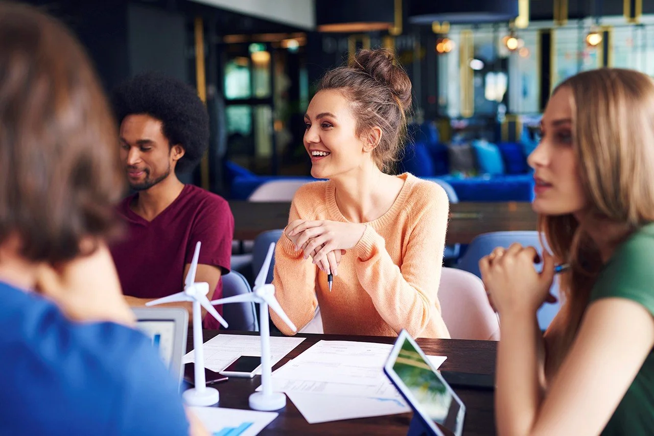 A team of young professionals, sitting around a meeting room table