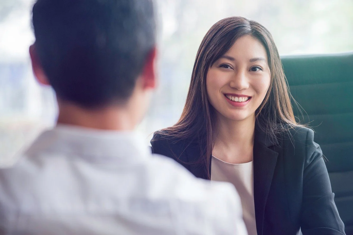 A young professional woman looking toward a man sitting across from her