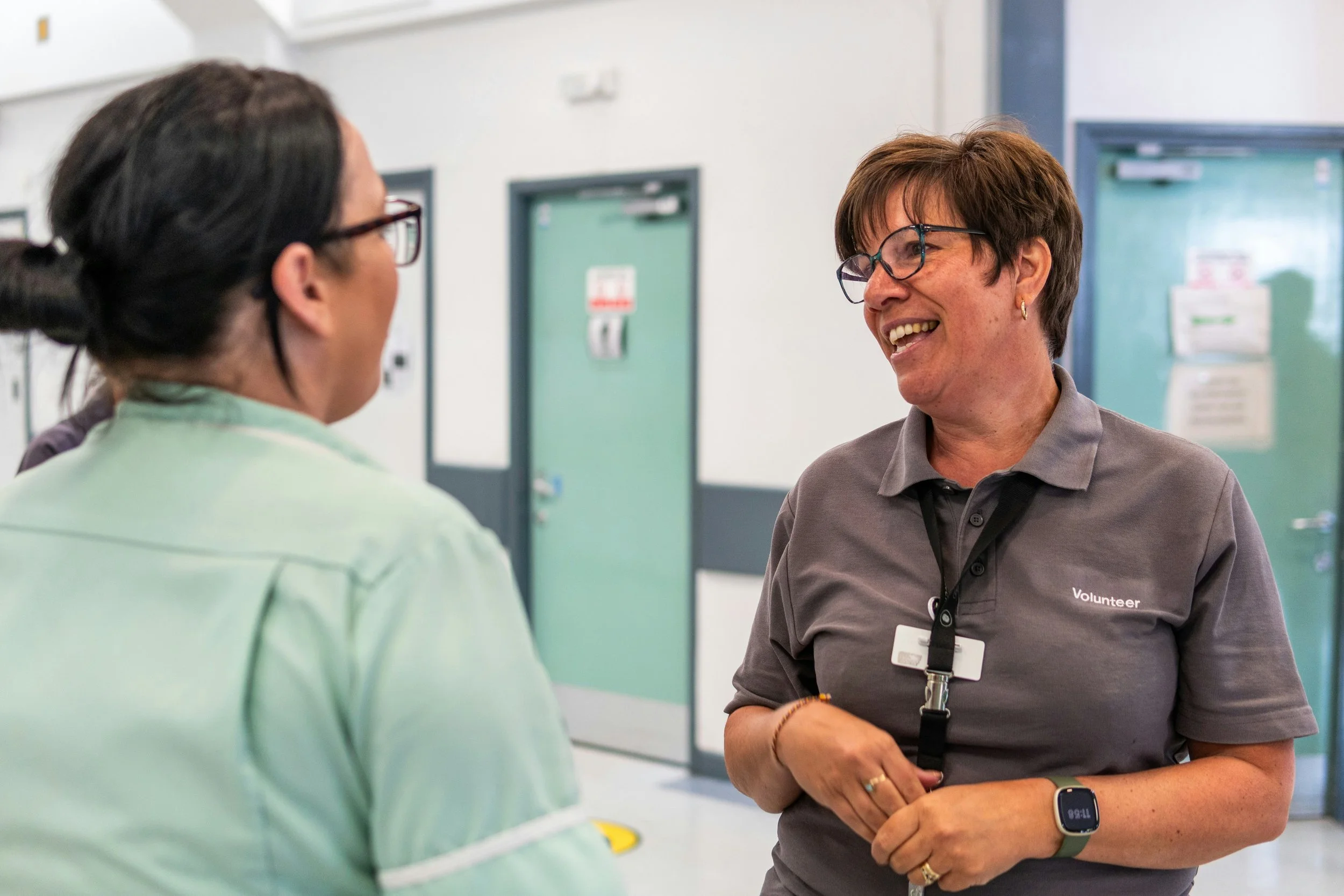 A healthcare professional and a volunteer having a conversation in a healthcare setting