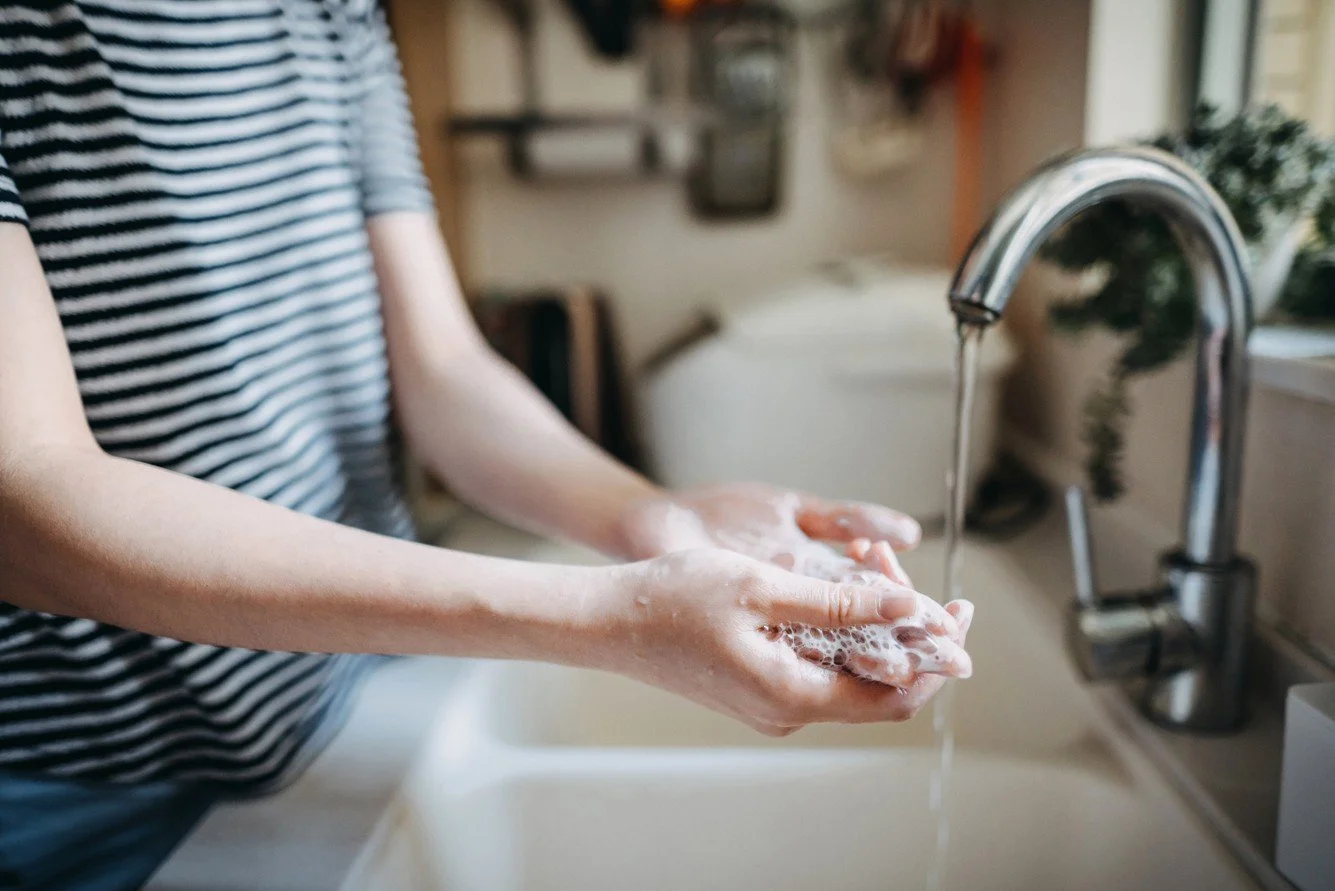 A cropped image of a woman washing her hands at a kitchen sink