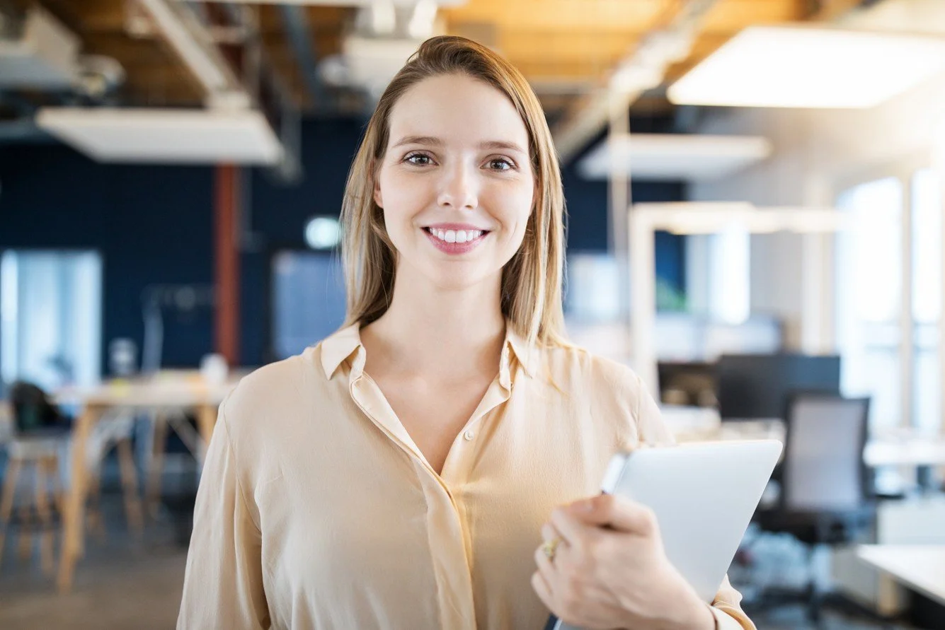 Portrait of a smiling young, professional woman standing in an office space