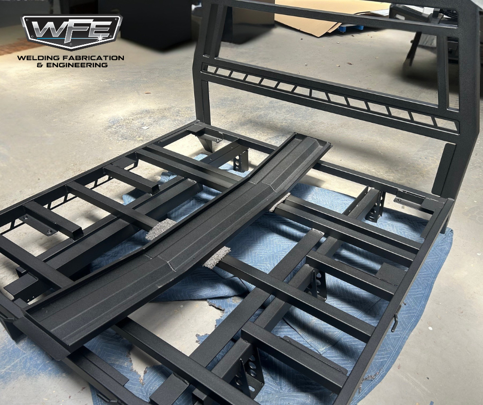 Metal bed frame in a workshop, with a black finish and structured support beams.