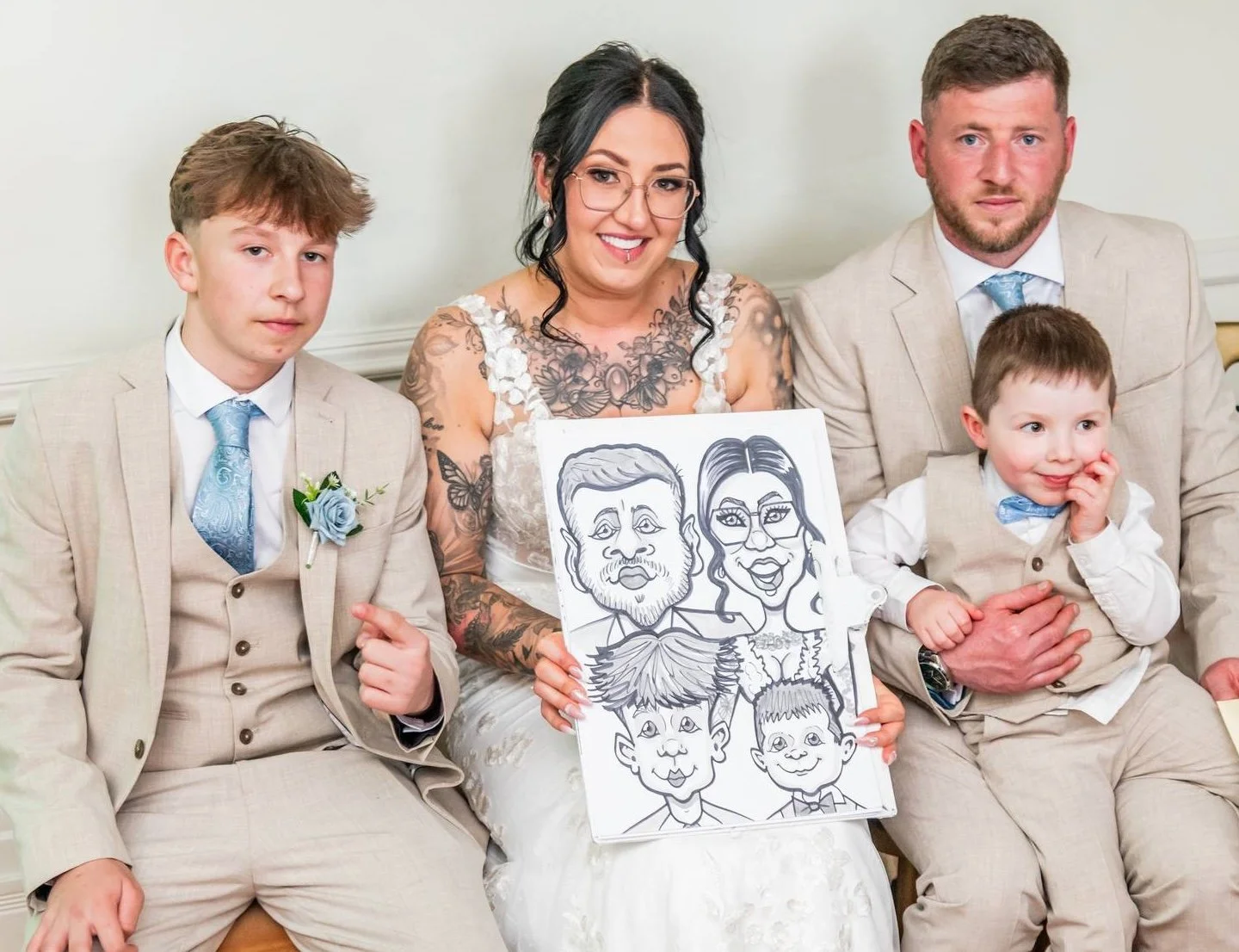 A family sitting on a couch at a wedding, holding a caricature drawing of themselves.