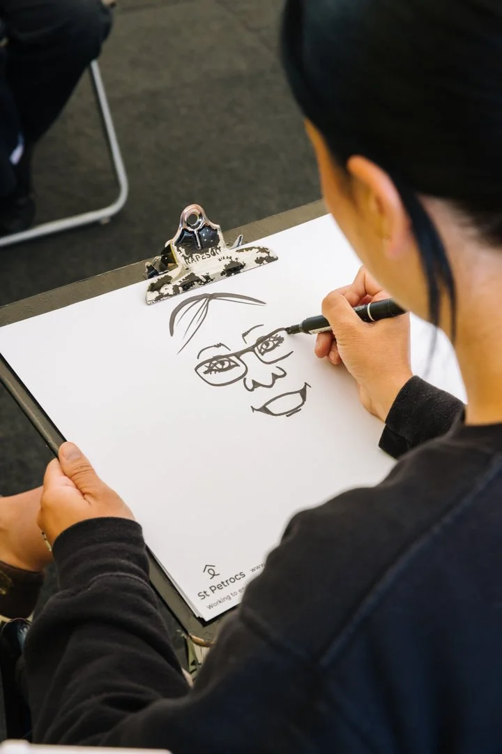 Person drawing a cartoon face with glasses on a clipboard.
