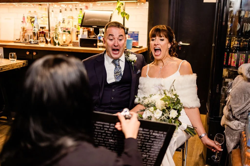 A bride and groom are surprised and happy during their wedding reception, as the caricature artist reveals their cartoon illustration.