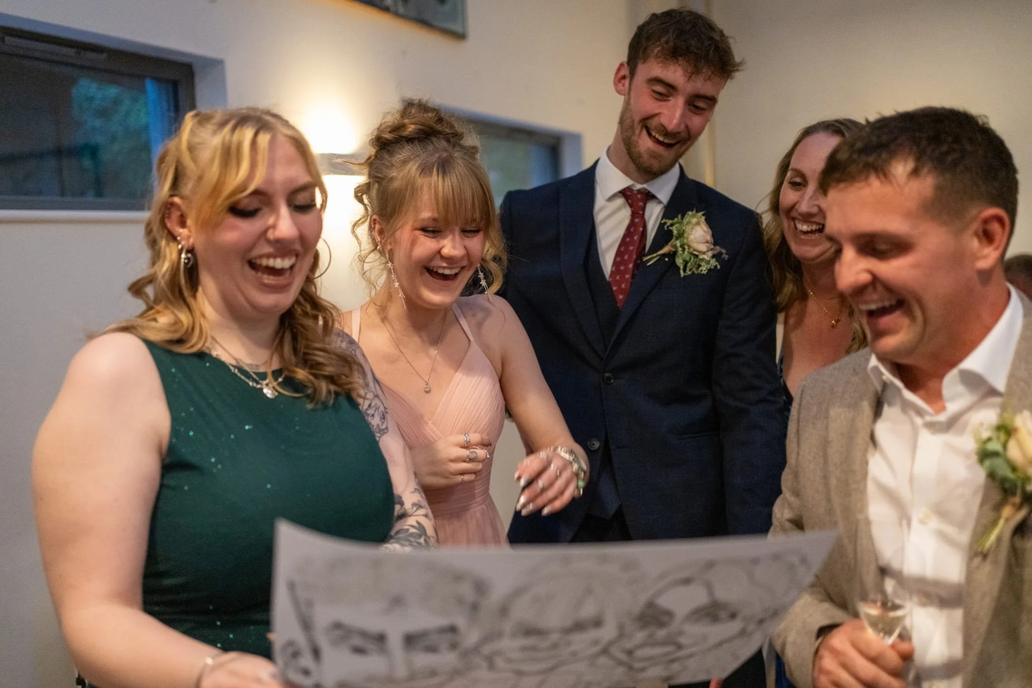 A group of six people dressed up, smiling, and gathered around a wedding caricature at a wedding reception.