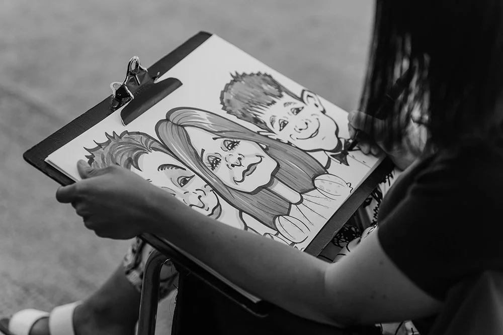 A person holding a clipboard with a caricature drawing of 3 children.