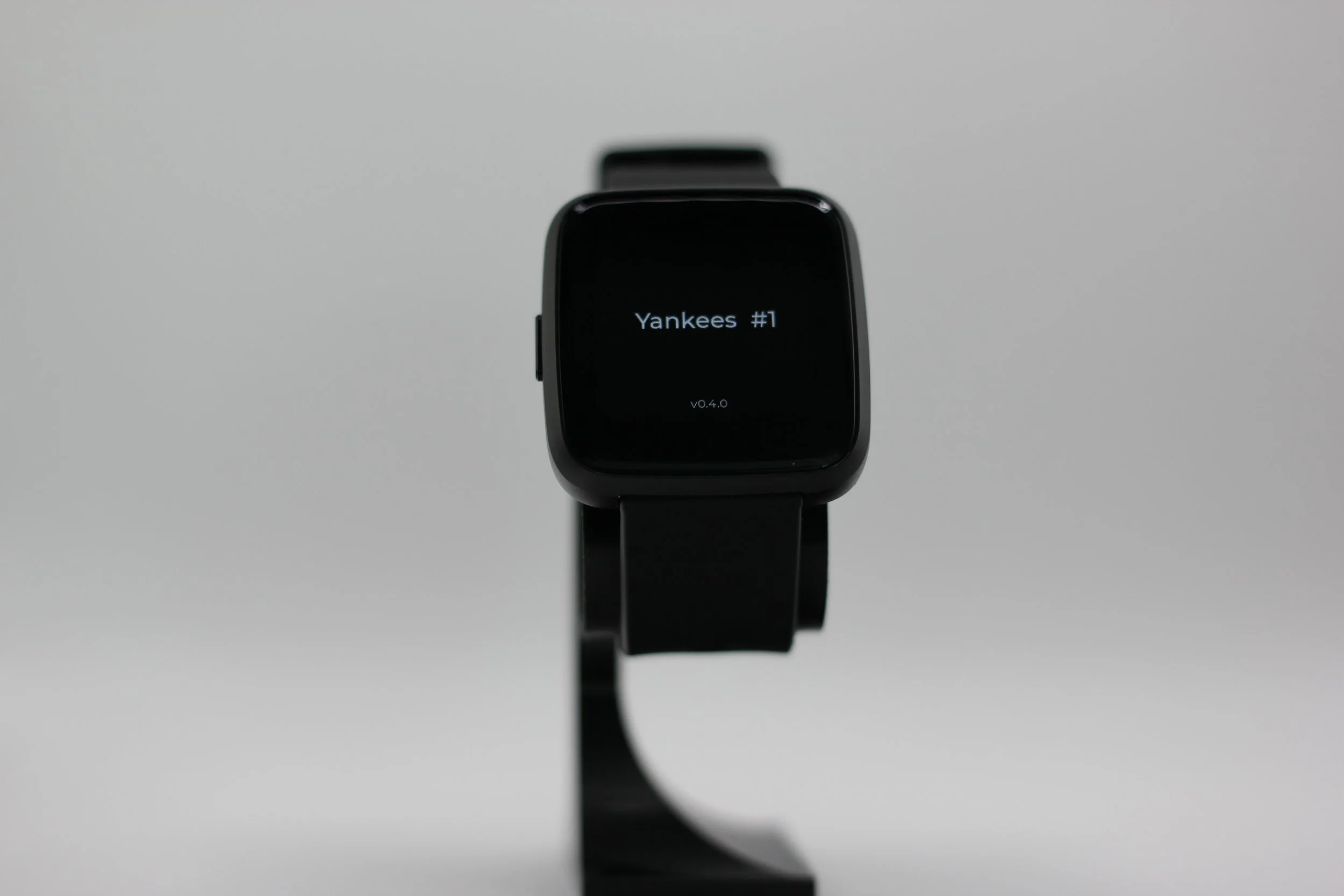 A black smartwatch displaying text that reads 'Yankees #1' with a gray background.