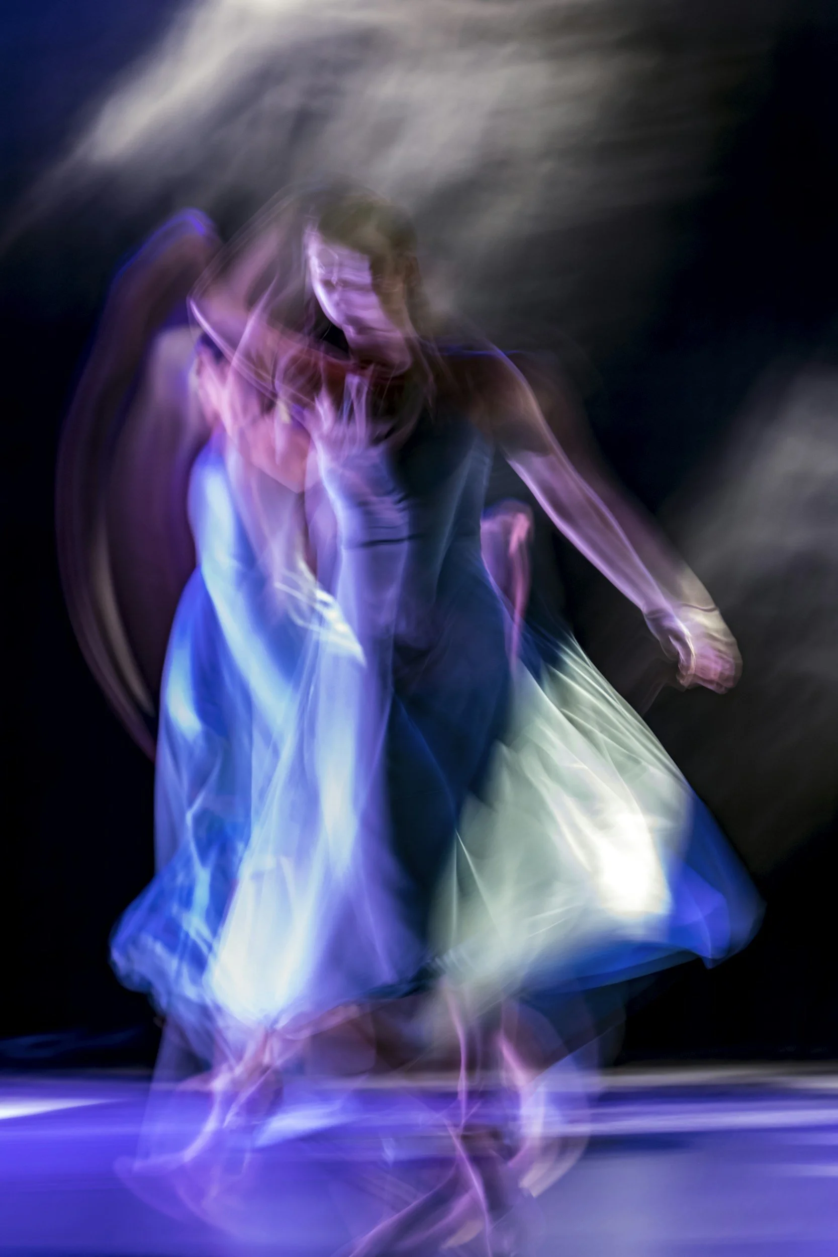 Abstract image with colorful swirling light trails, primarily in purple, blue, and pink hues, against a dark background.