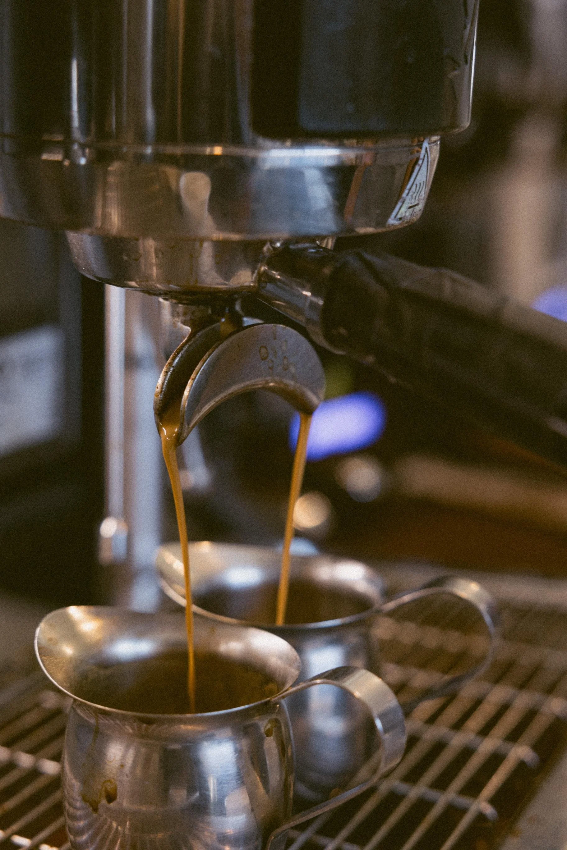 Espresso machine pouring coffee into a small metal cup.