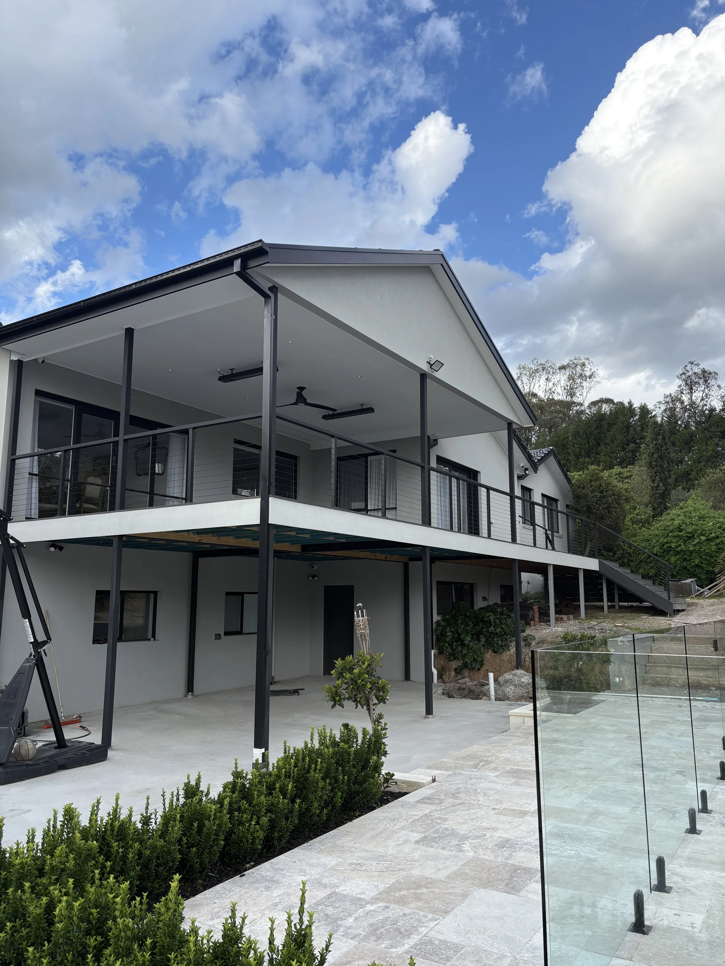 custom home build in Melbourne: Modern house with a large balcony and a paved patio area