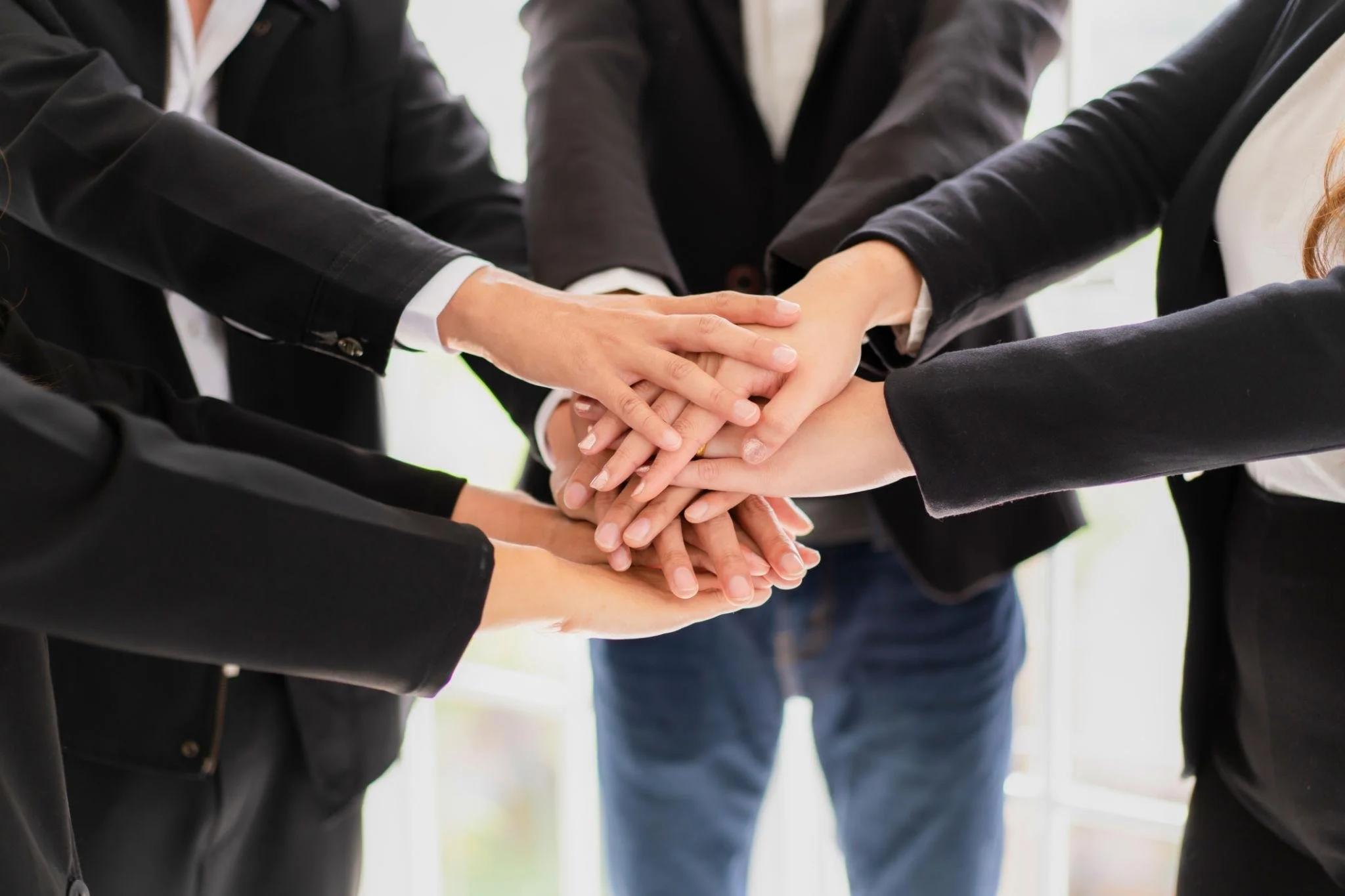 Group of people with hands stacked together in a team-building gesture.