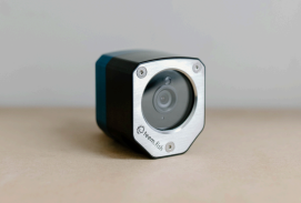 Small security camera with black and white casing on a beige surface