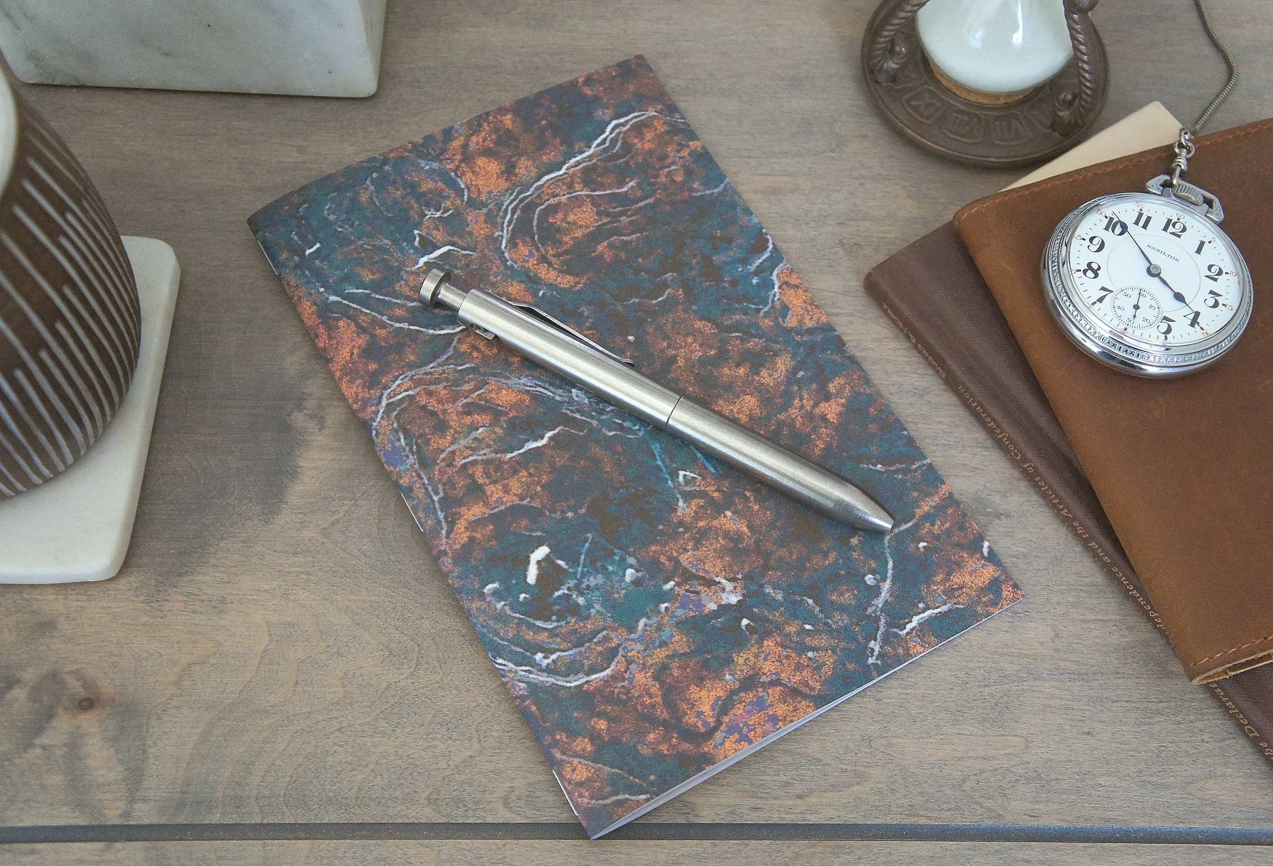 The depiction of mossy stone adorns the outside of a 5 inch by 7 inch softcover journal, handmade in New London, New Hampshire by the Munk Mint