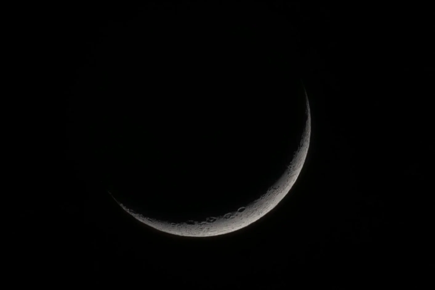 A crescent moon with visible surface details against a dark night sky.