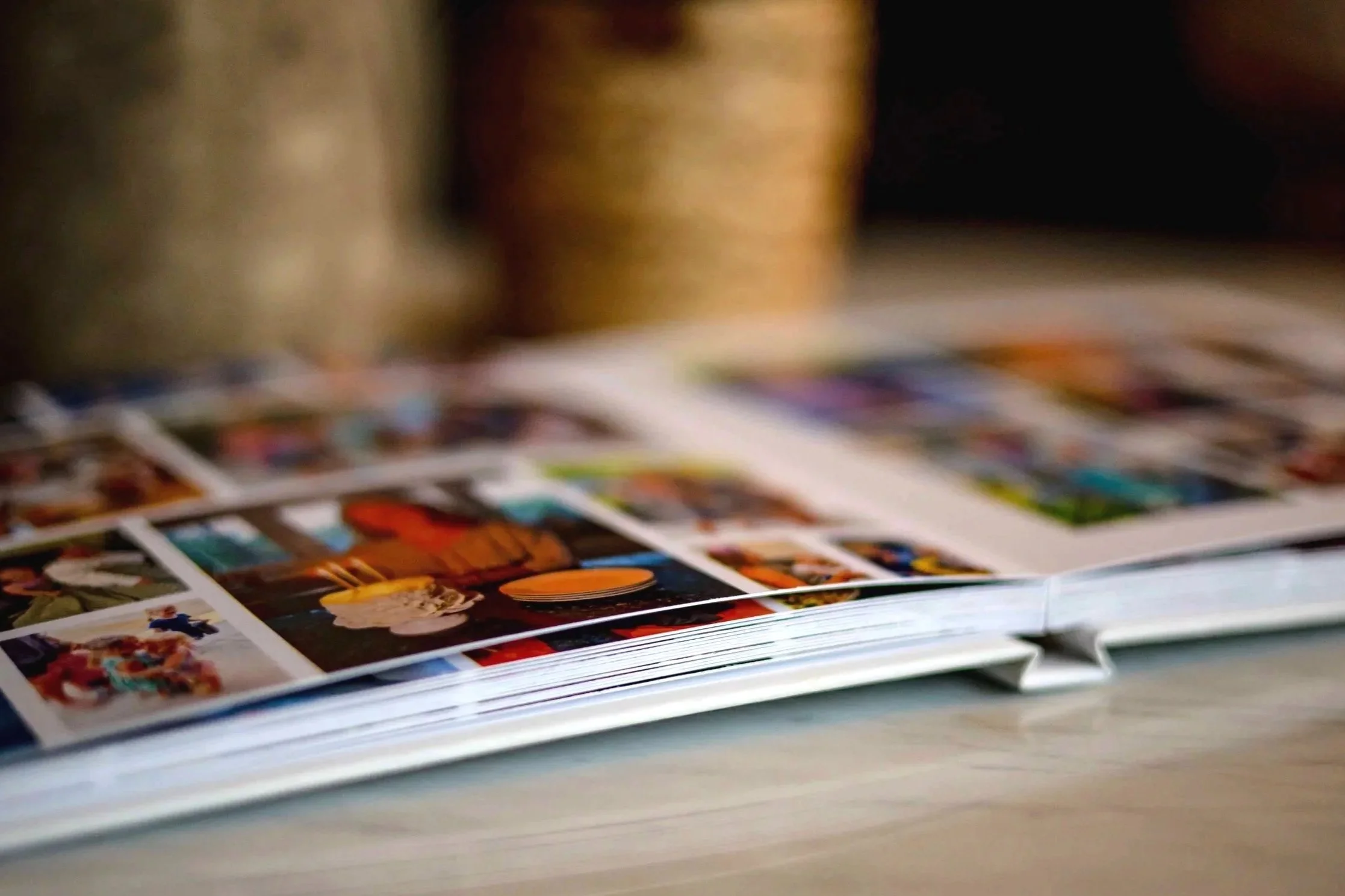 Close-up of a magazine or photo album with glossy pages displaying colorful photographs, lying on a flat surface.