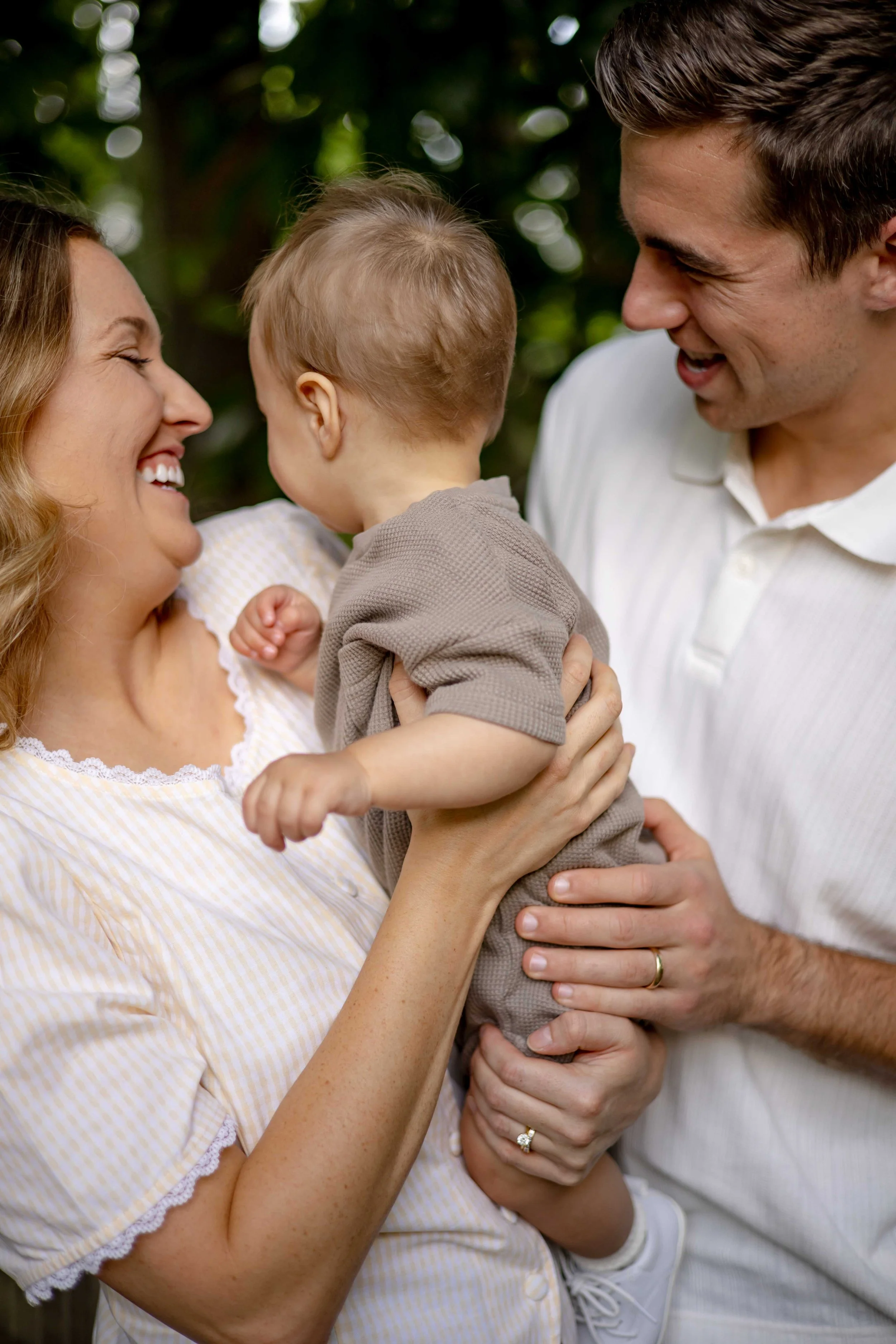 Parents laughing while holding baby