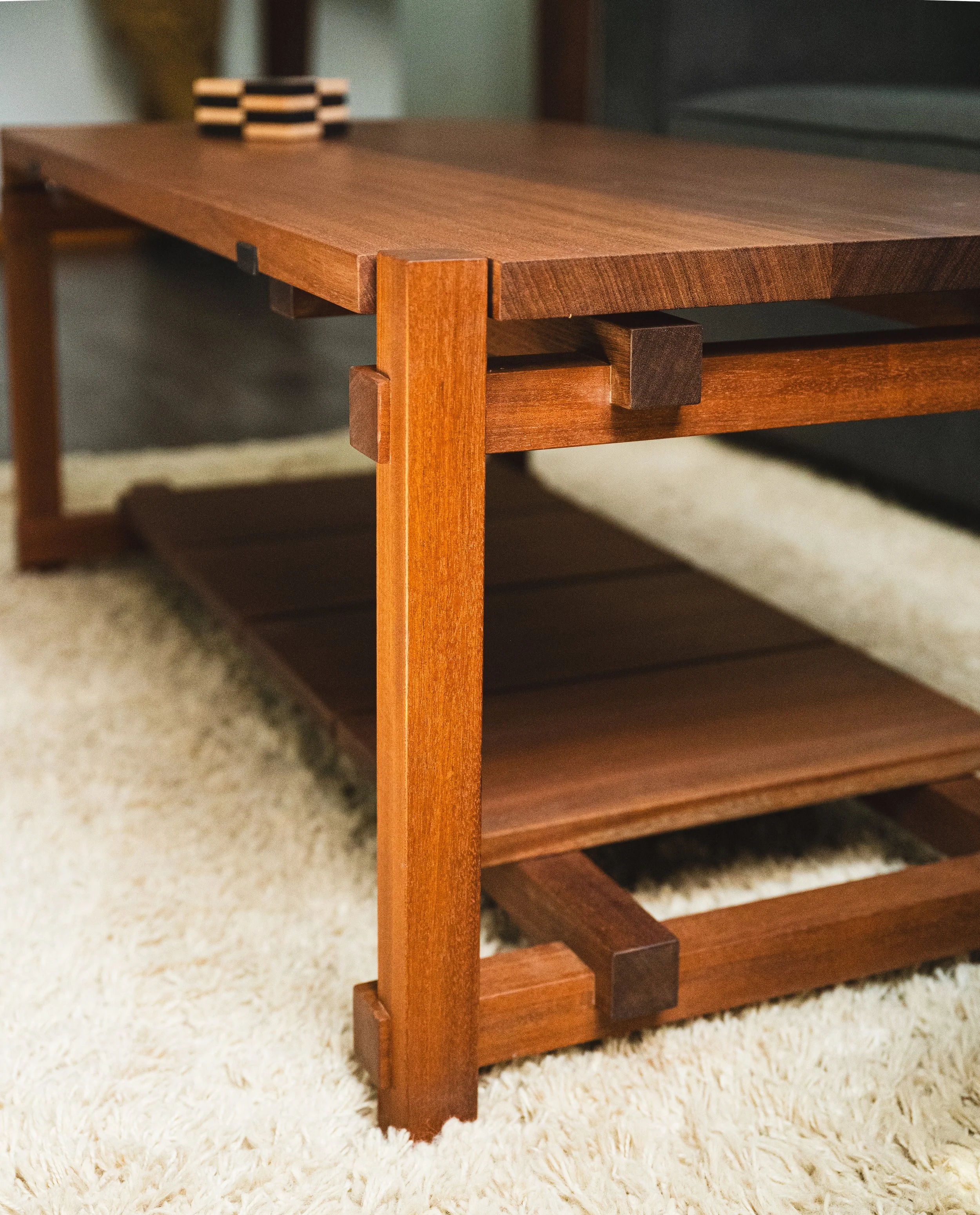 Close-up of a wooden table with a small stack of black and white coasters, placed on a light-colored carpeted floor.