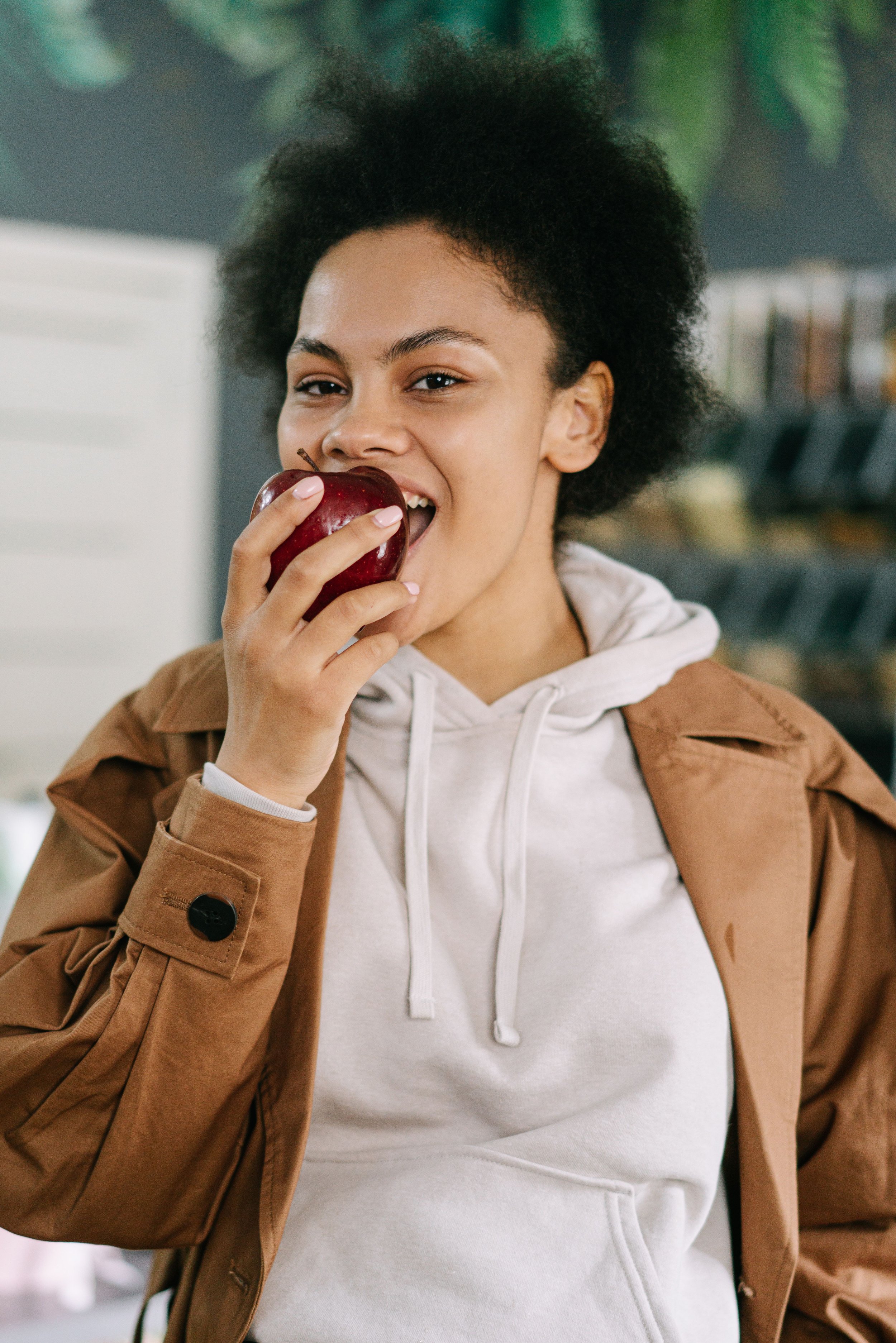 Young woman enjoying a fresh apple while shopping — everyday balanced eating