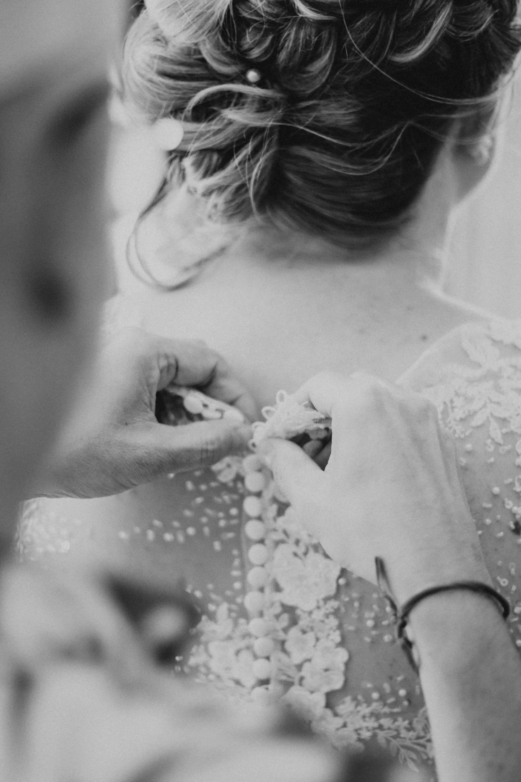 A bride with her hair styled on her wedding day with someone assisting  her with the back of her dress before walking down the aisle in a Simcoe-Muskoka Wedding Venue.