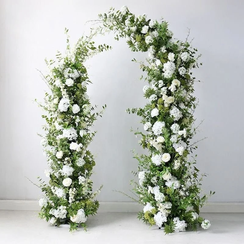 A tall, decorative floral arch designed with white flowers and green foliage, set against a white washed wall at Braestone Farm.